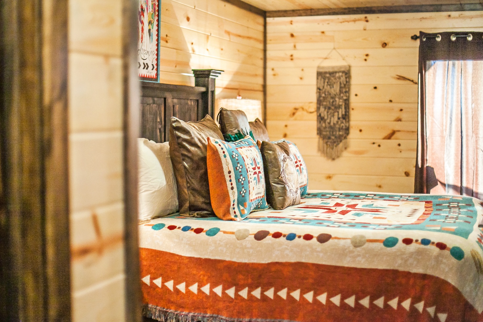 Sink into cozy Native American-inspired bedding surrounded by warm wood cabin walls that create your perfect mountain retreat atmosphere.