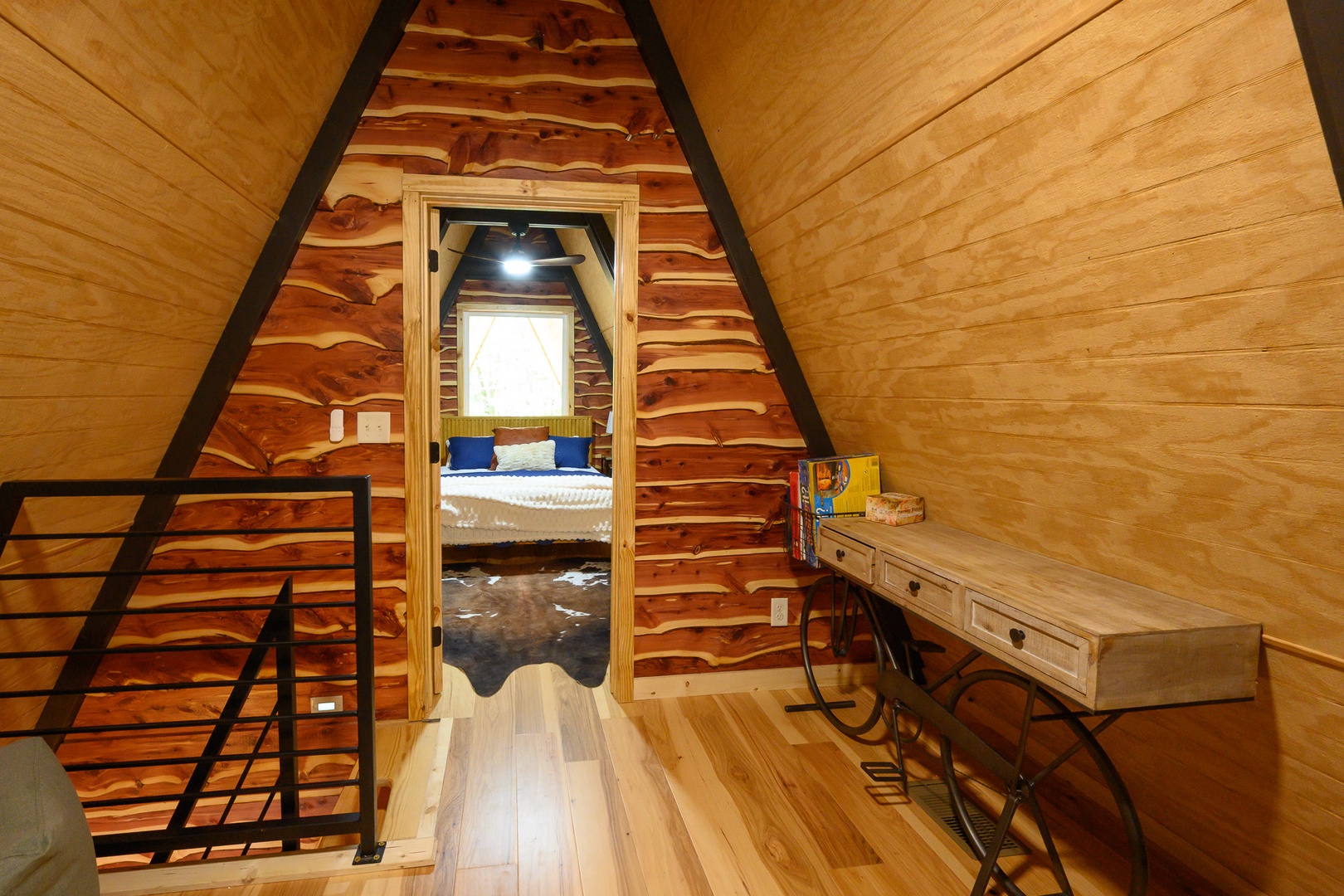 Step into your own cozy A-frame sanctuary, where warm wood tones and thoughtful touches create the perfect mountain retreat. The inviting bedroom beckons through the doorway, promising restful nights under the peaked ceiling.