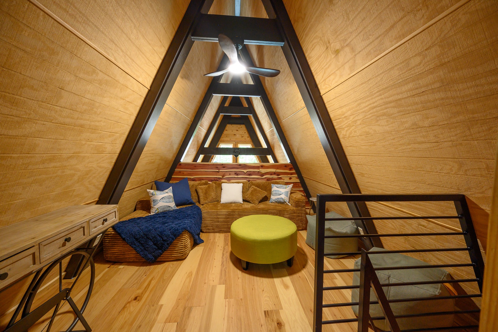 Look up to the soaring A-frame ceiling that frames your cozy retreat. Sink into the woven seating nook with your favorite book, or gather around the bright ottoman for evening conversation under the warm glow of the ceiling fan above.