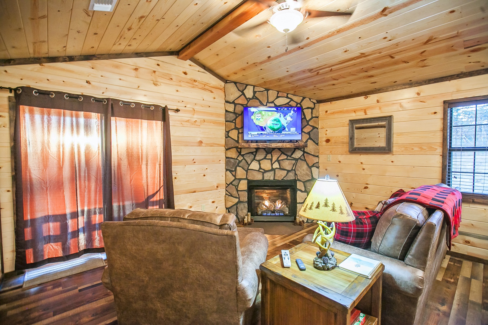 Cozy up by your stone fireplace while watching TV in this rustic living room with warm wood accents.