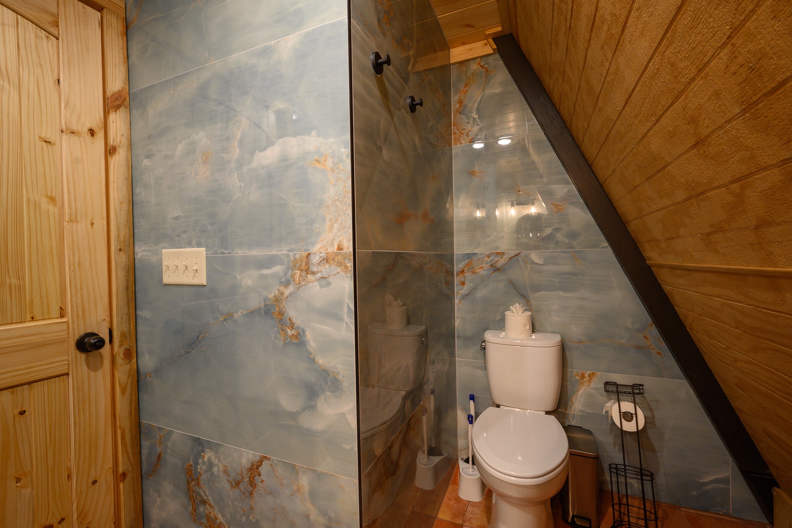 Your private bathroom features a rainfall shower, modern fixtures, and unique marbled tile walls that add a serene, spa-like atmosphere to your mountain retreat.