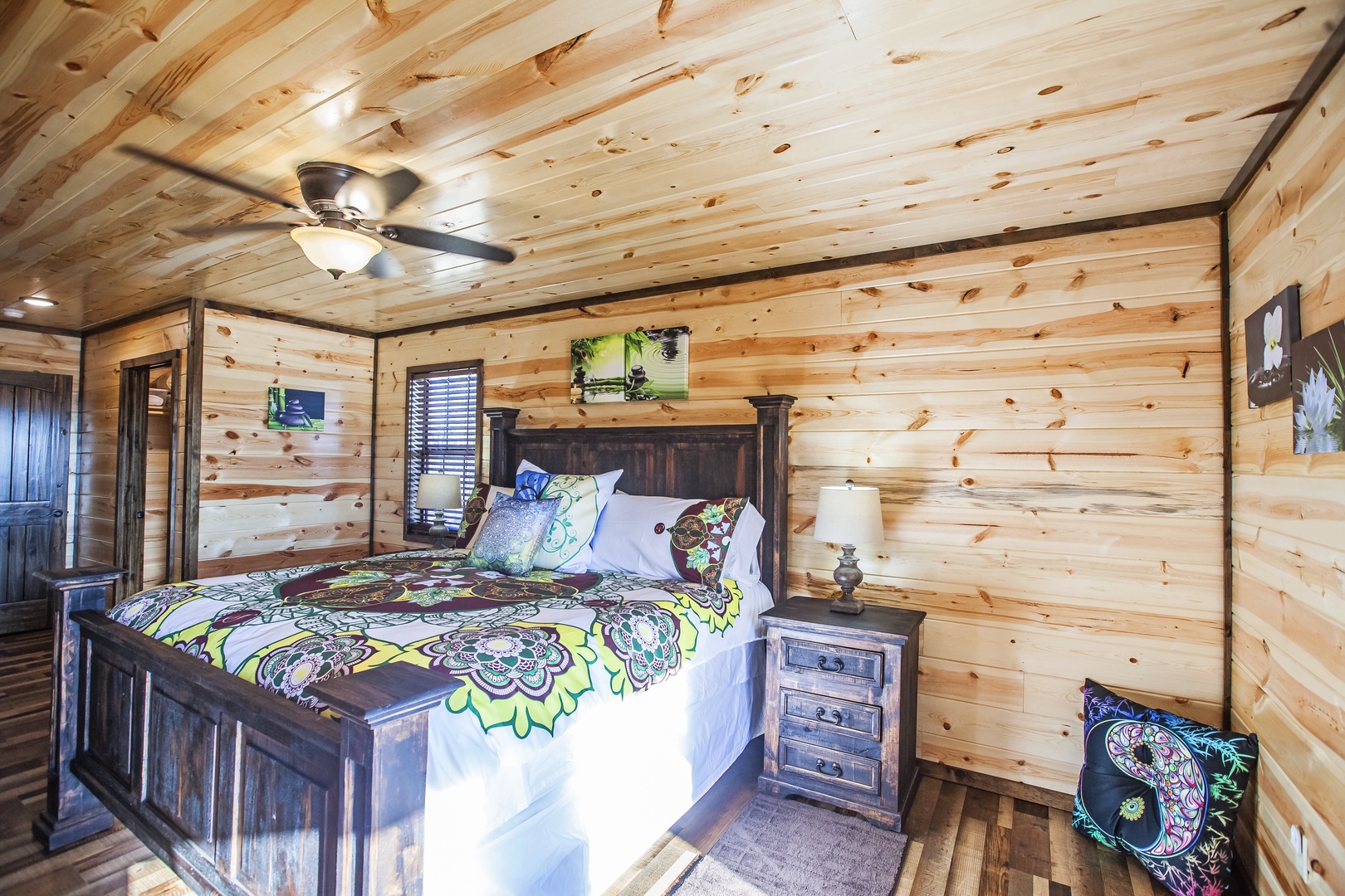 Rustic knotty pine walls surround your cozy retreat, where vibrant bedding and rustic furnishings create warmth beneath the gentle ceiling fan breeze.