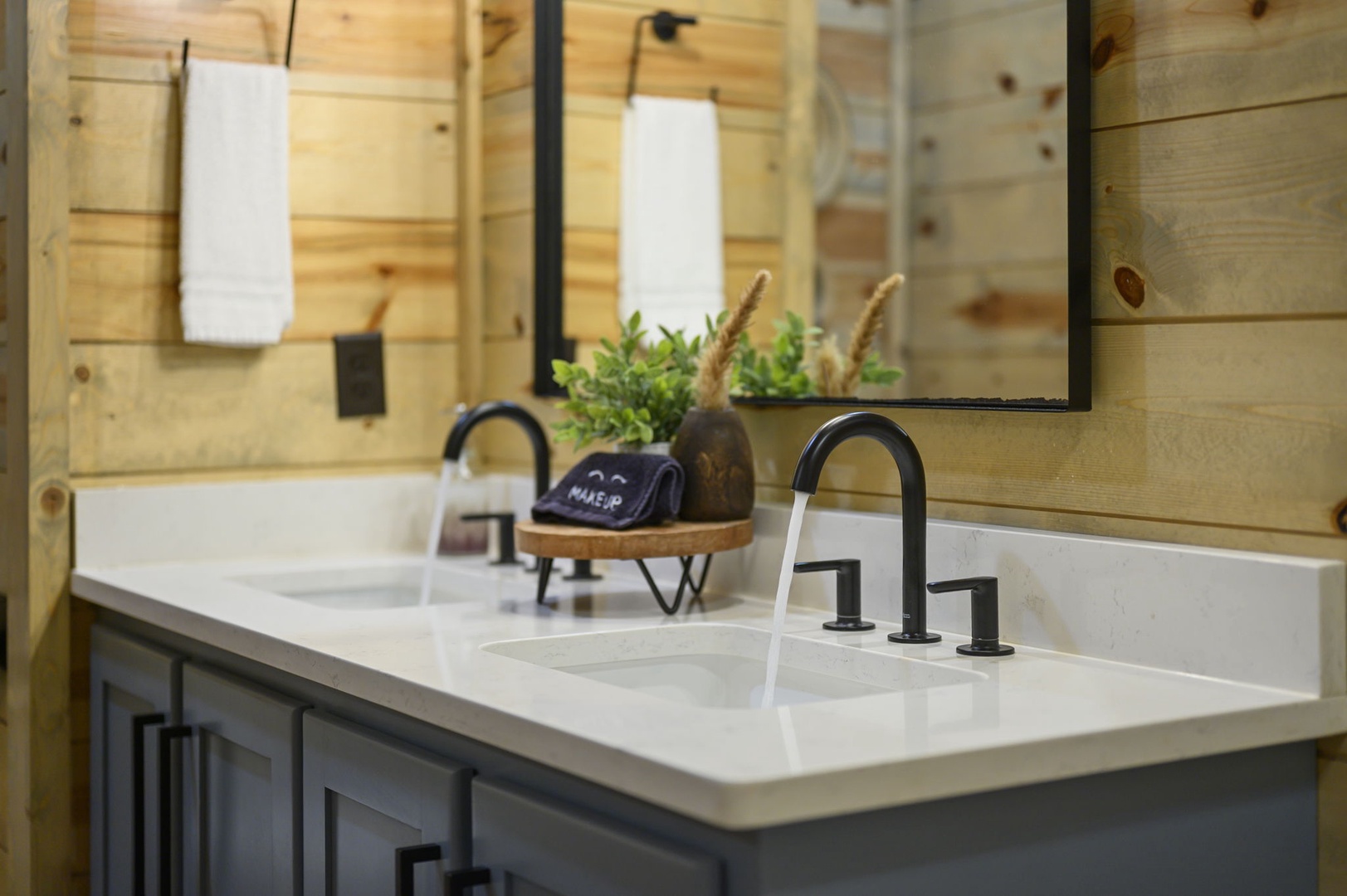 Step into your private bathroom with warm wood accents, dual sinks with sleek black fixtures, and a thoughtful makeup station ready for your morning routine.