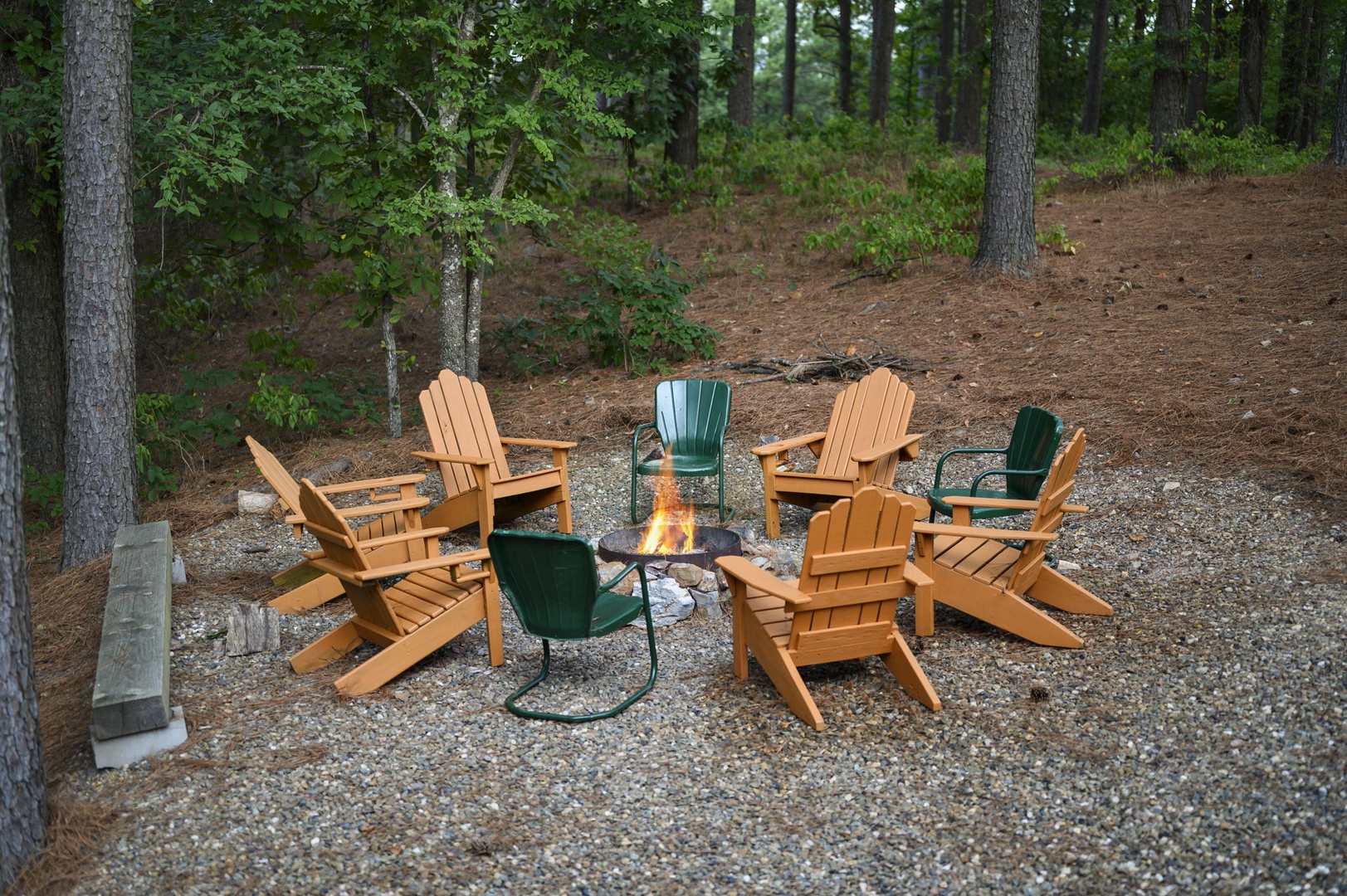 A circle of Adirondack chairs surrounds a fire pit nestled in the trees—perfect for sharing stories under the stars or enjoying your morning coffee in peaceful woodland solitude.