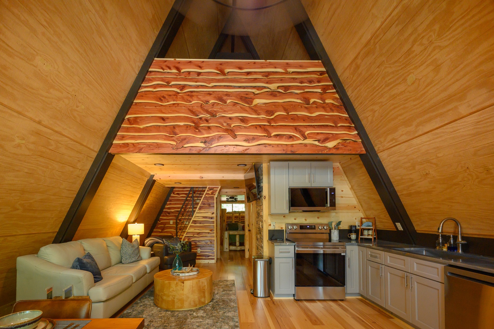 Step into your cozy A-frame retreat, where warm wood tones wrap around you and a unique loft beckons above. Your kitchen stands ready for home-cooked meals, while your living space invites you to unwind by soft lamplight.