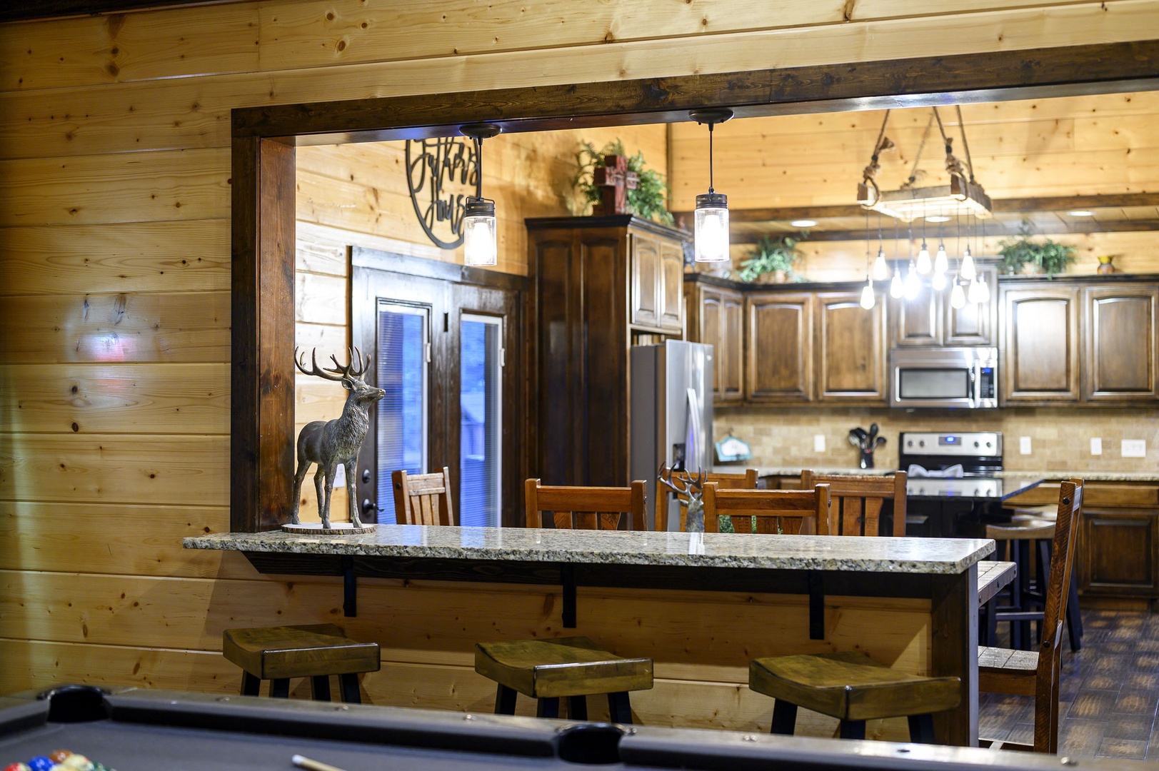 Gather around the rustic breakfast bar with granite countertop and warm wood tones. The open layout connects to a fully-equipped kitchen, perfect for morning coffee or evening conversations.