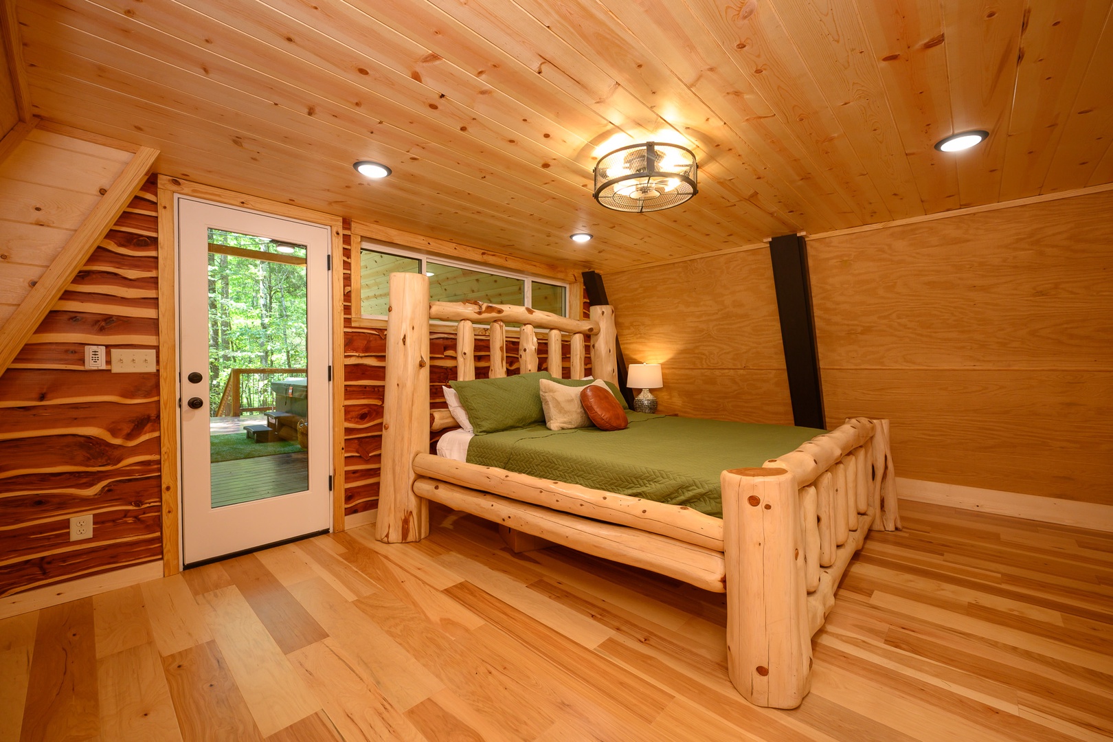 Your cozy cabin retreat features a handcrafted log bed under warm pine ceilings, with glass doors opening to your private deck surrounded by forest views.
