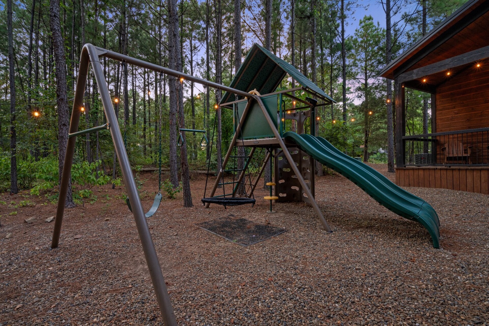 A private playground nestled among towering pines awaits your little adventurers, complete with swings, slide, and climbing features—all surrounded by the peaceful forest setting.