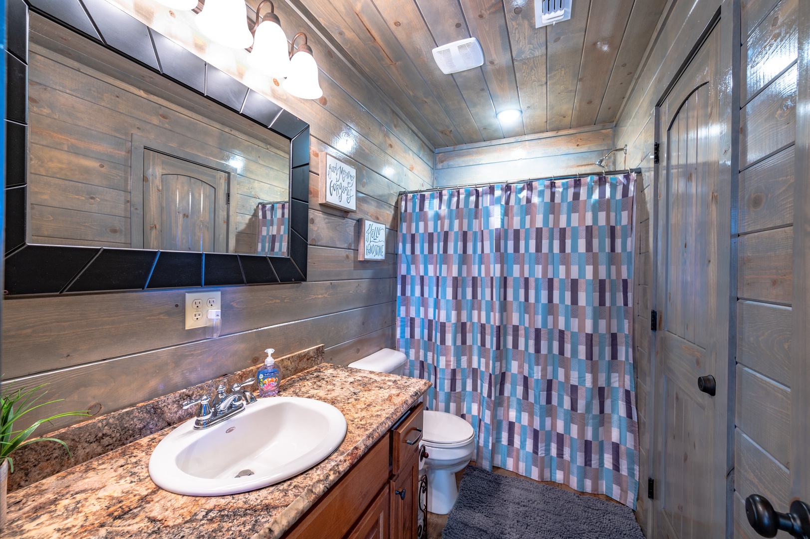 Step into your rustic bathroom with granite countertops and charming wood-paneled walls that create a cozy mountain retreat atmosphere.