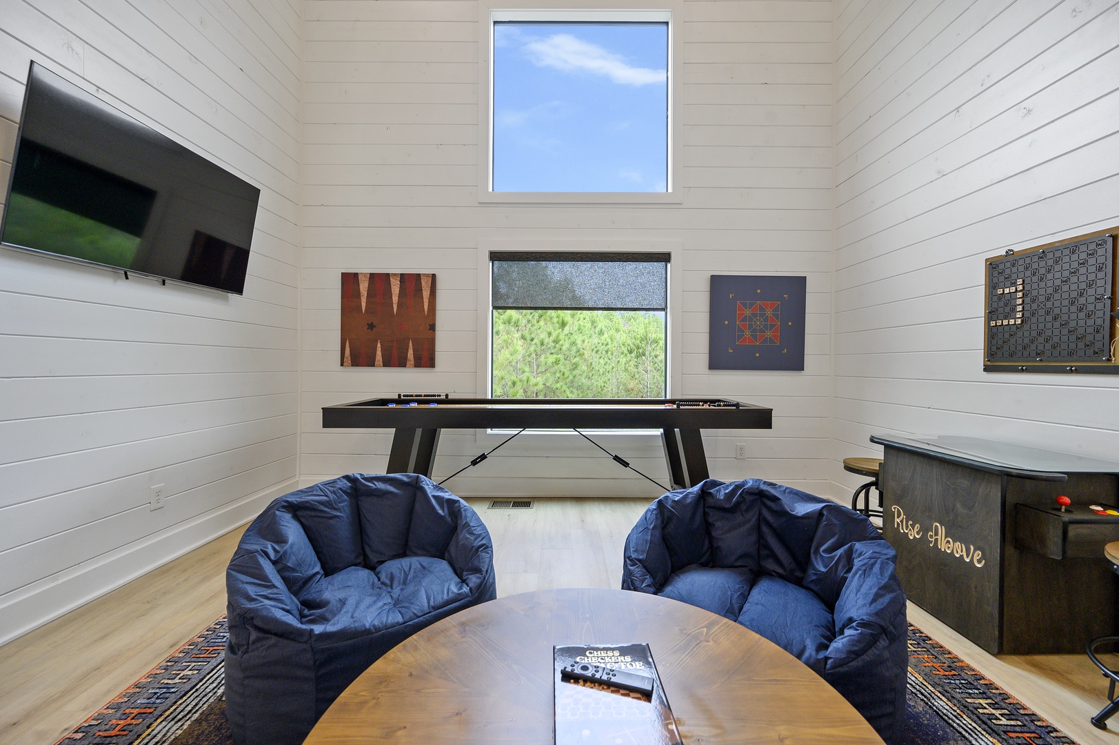 Your game room features comfy bean bags, vintage arcade games, and board games for endless entertainment under natural light.