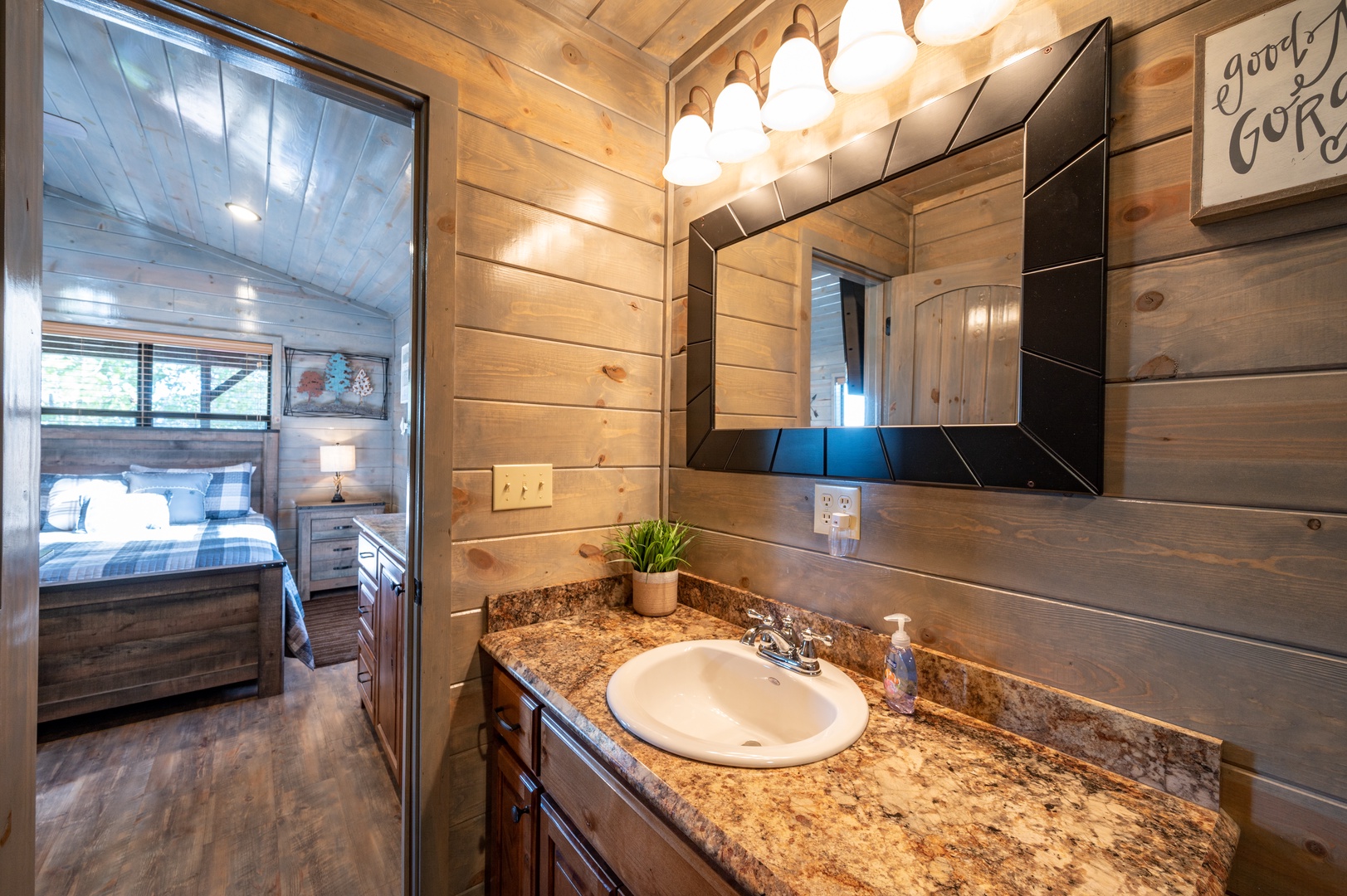 Step into your private bathroom featuring granite countertops and rustic wood walls, with your cozy bedroom just steps away.