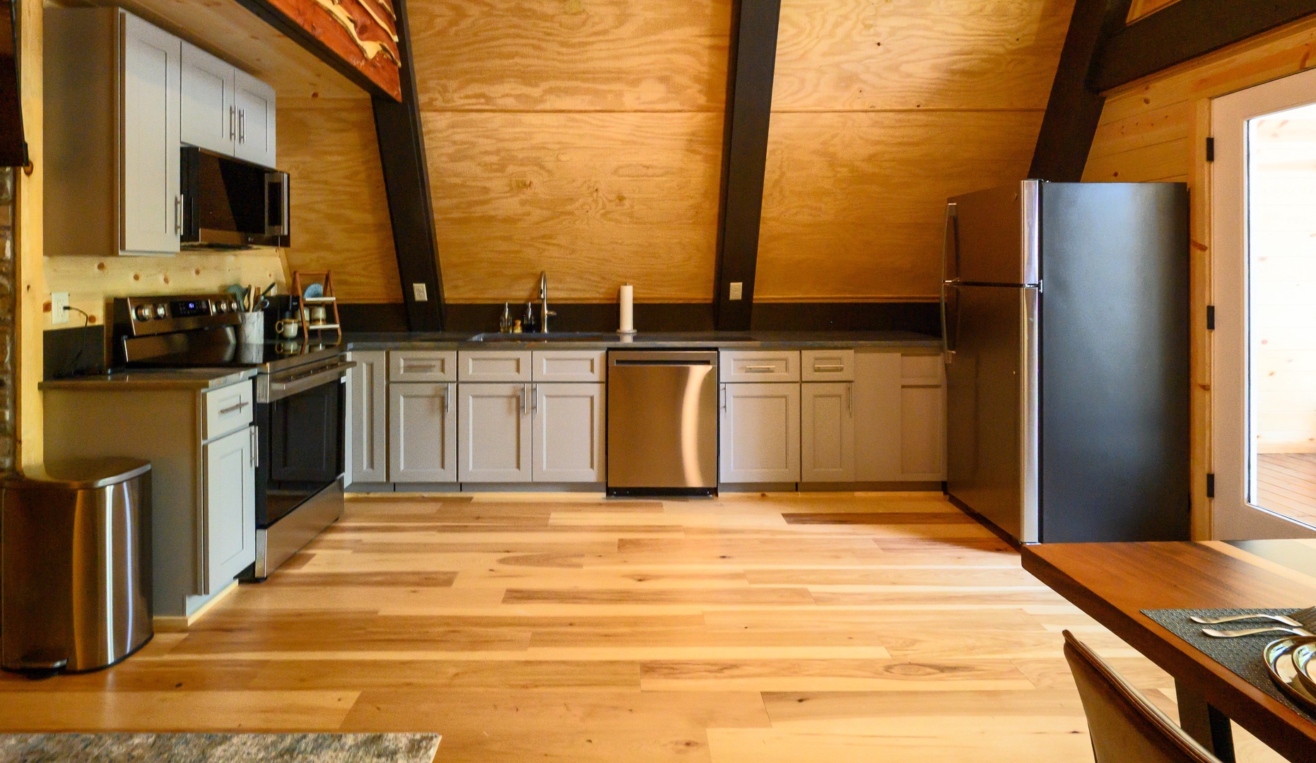 Your fully equipped kitchen features modern appliances and ample counter space beneath warm wood vaulted ceilings, creating an inviting space to prepare meals during your stay.