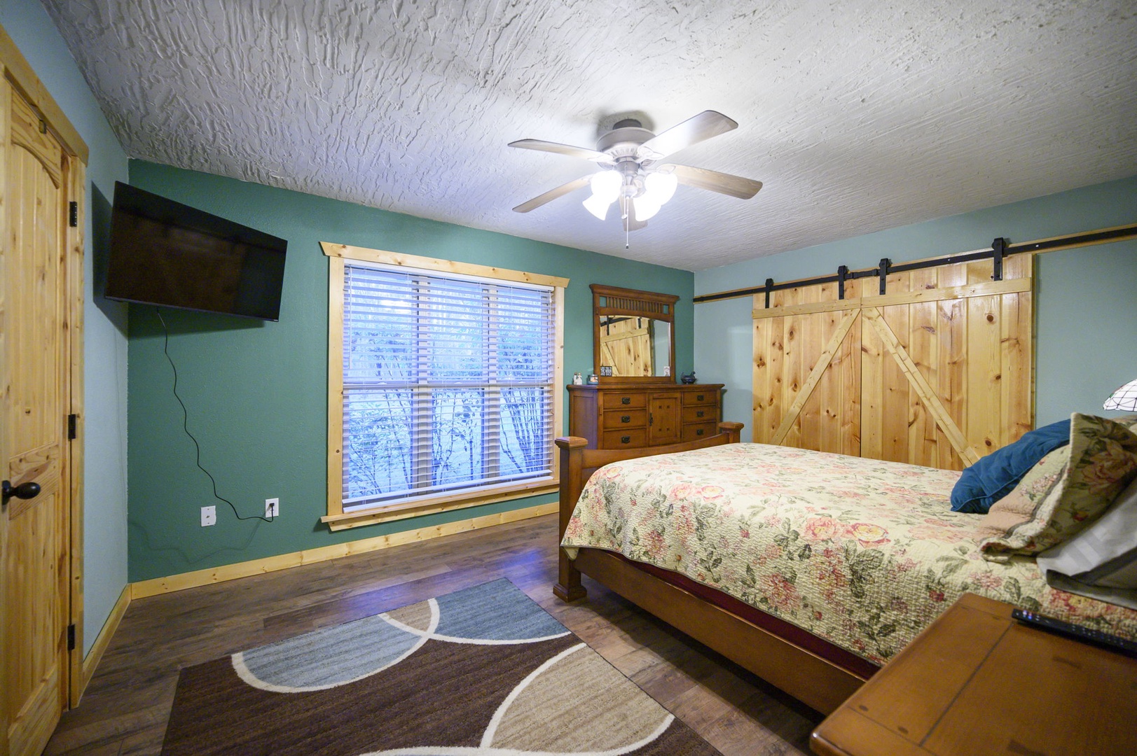 Unwind in your cozy bedroom featuring rustic barn doors, warm wood accents, and a ceiling fan for perfect comfort.
