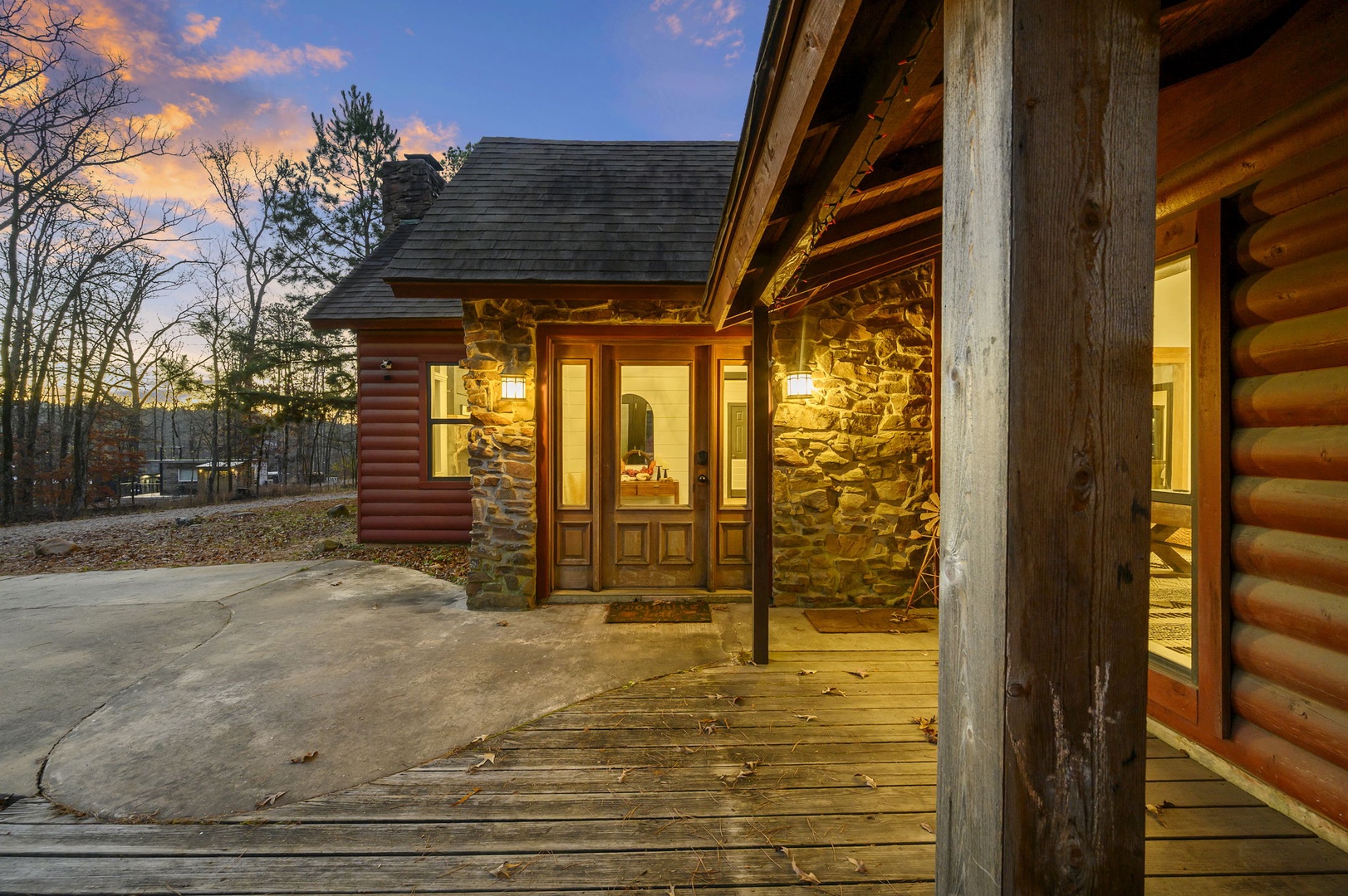 Rustic log cabin with stone accents and covered porch creates a welcoming mountain retreat at twilight.