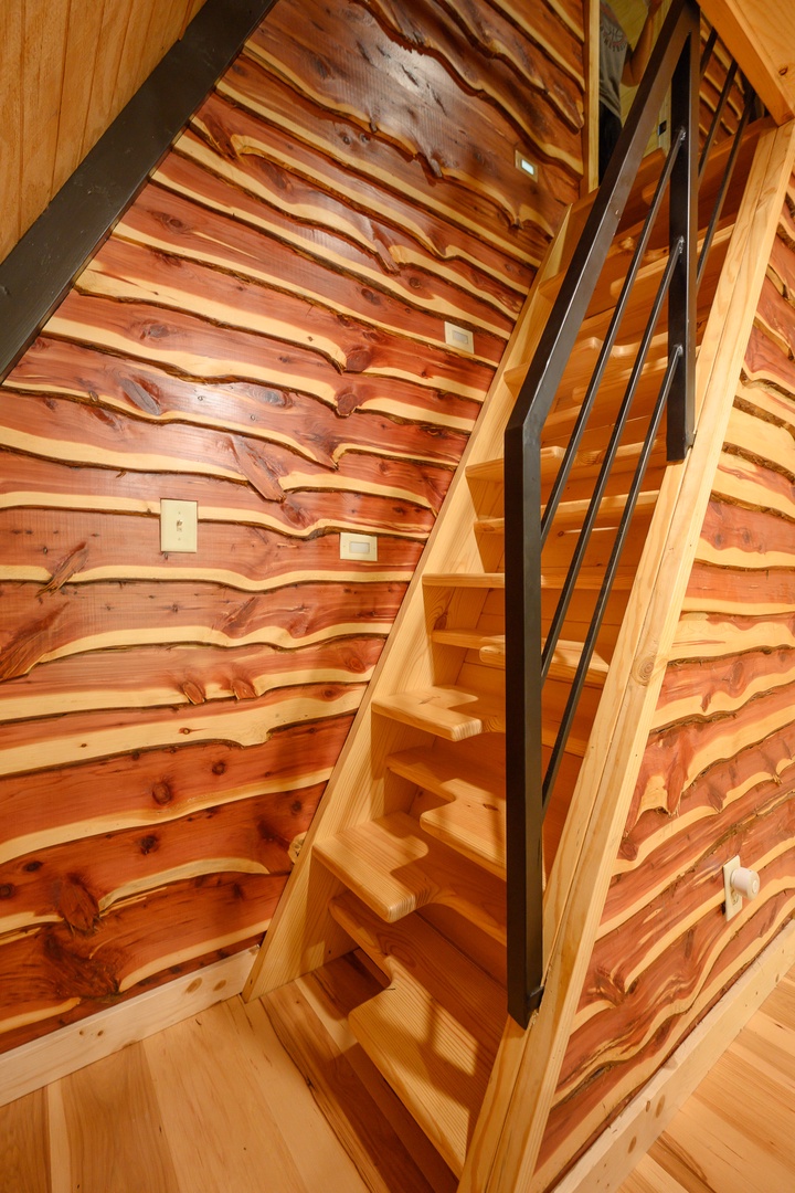 Handcrafted cedar stairs with black metal railing showcase the natural beauty of the wood.