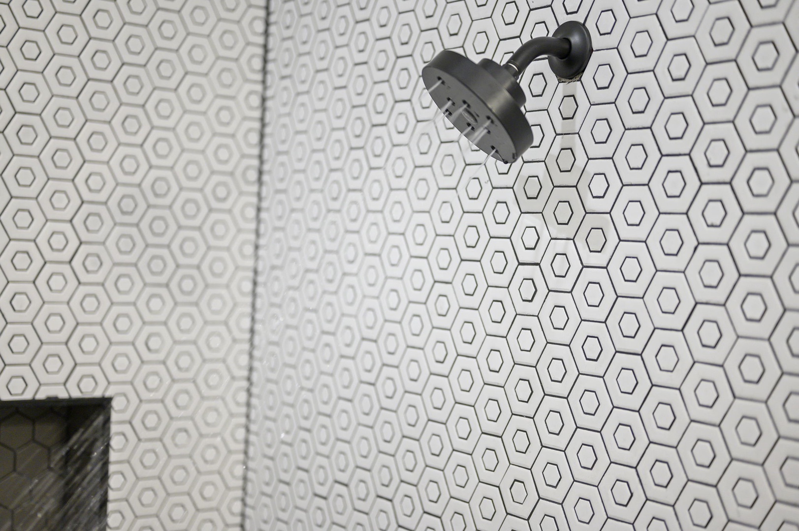 Step into your stylish shower featuring geometric hexagon tiles and modern black fixtures for a refreshing start to your day.
