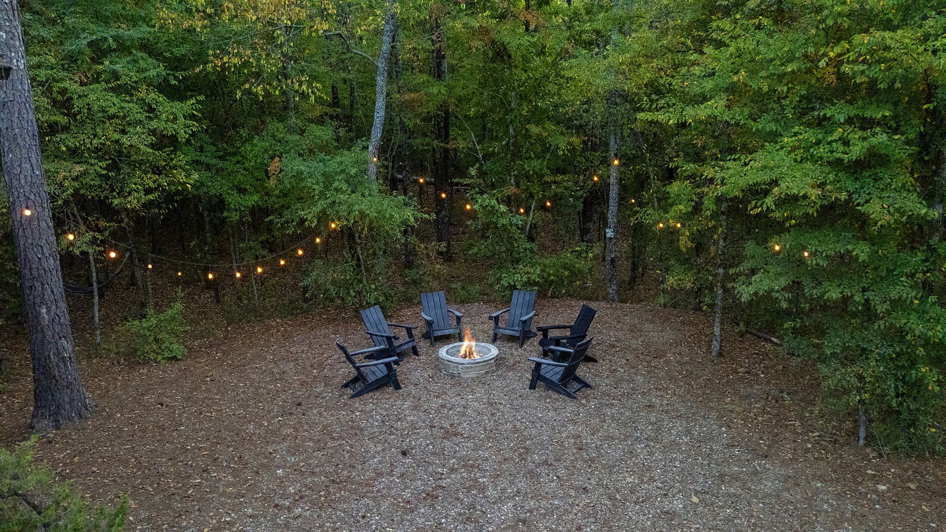 Your private fire pit awaits, nestled among towering trees and lit by string lights, creating a peaceful spot to gather, unwind, and enjoy cozy evenings under the stars.