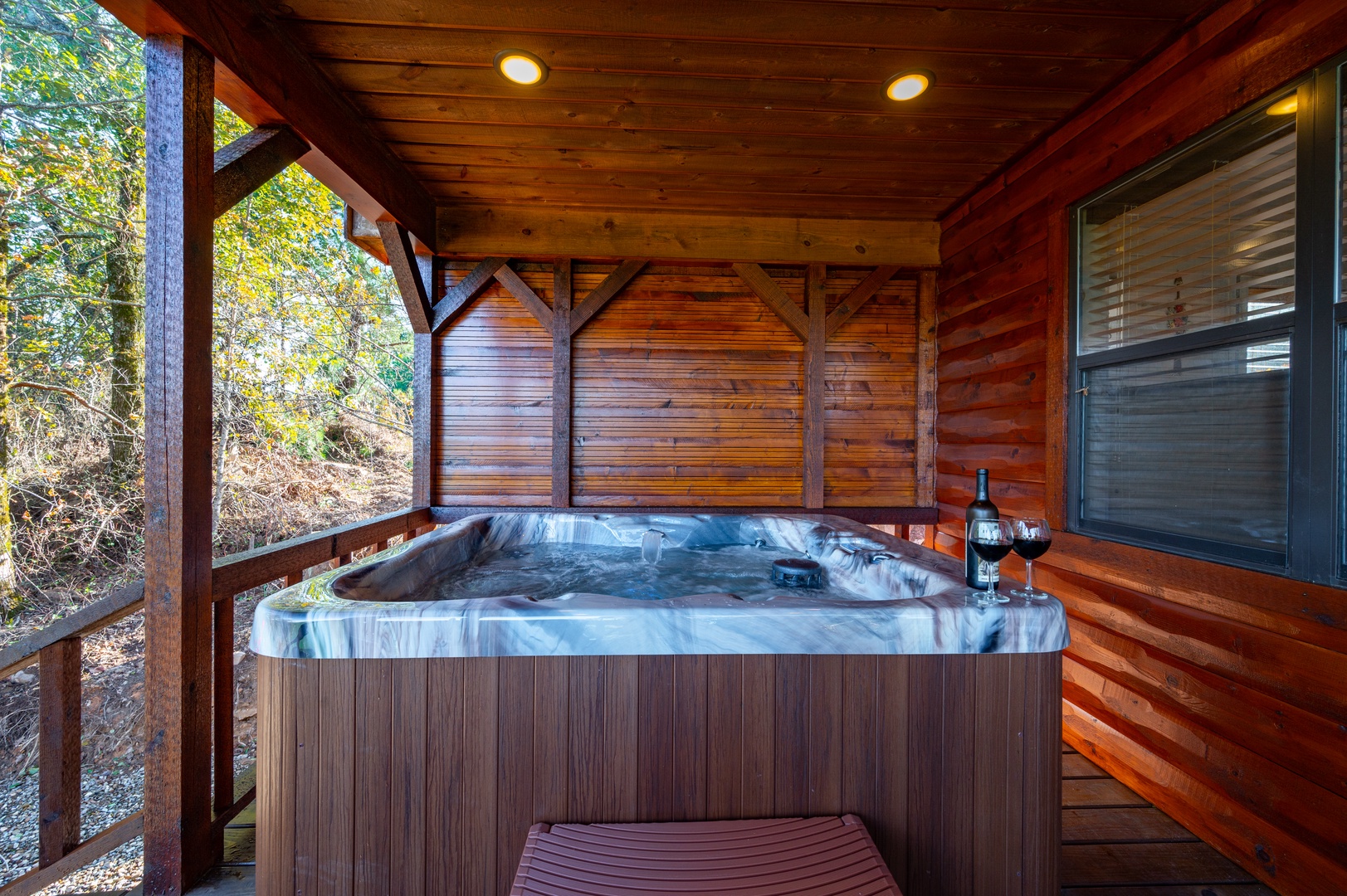 Sink into your private hot tub surrounded by warm wood and forest views, perfect for unwinding with wine after exploring.