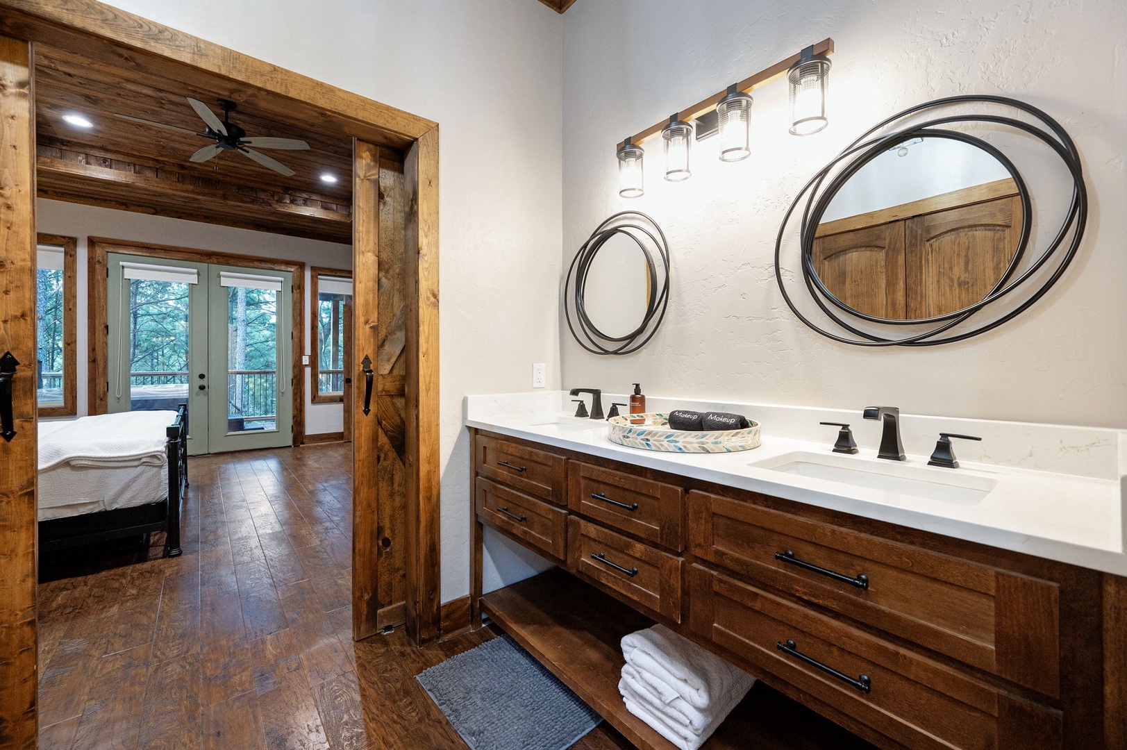 Your private bathroom features rustic elegance with a sleek double vanity, warm wood cabinetry, and soft lighting—perfectly designed for peaceful mornings and evenings.