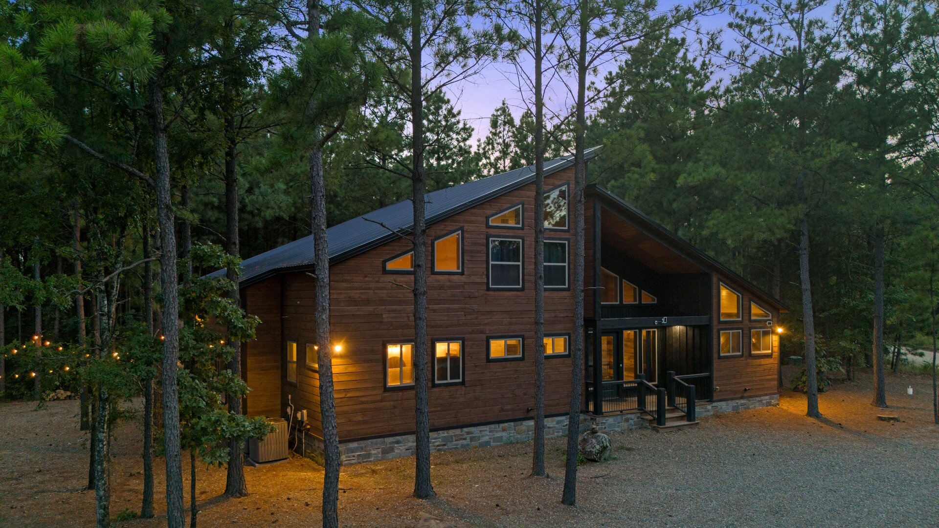 A stunning modern cabin nestled among towering pines, illuminated at dusk as the forest surrounds your private woodland retreat.