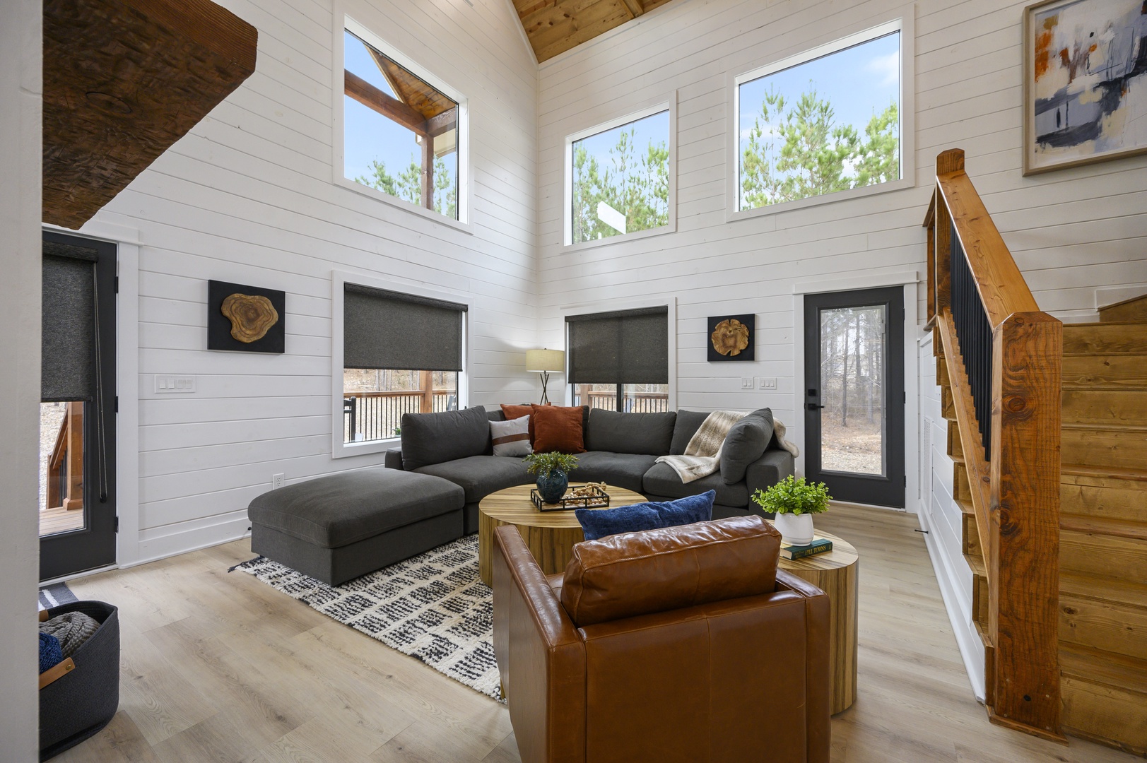 Sink into plush seating in your stunning living room, where natural light streams through soaring windows and rustic wood beams create warmth above.