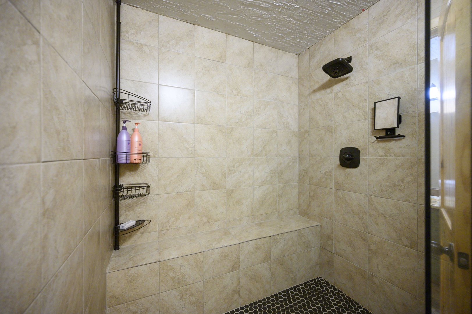 Step into your luxurious marble-tiled shower with rainfall head and convenient storage caddy for your toiletries.