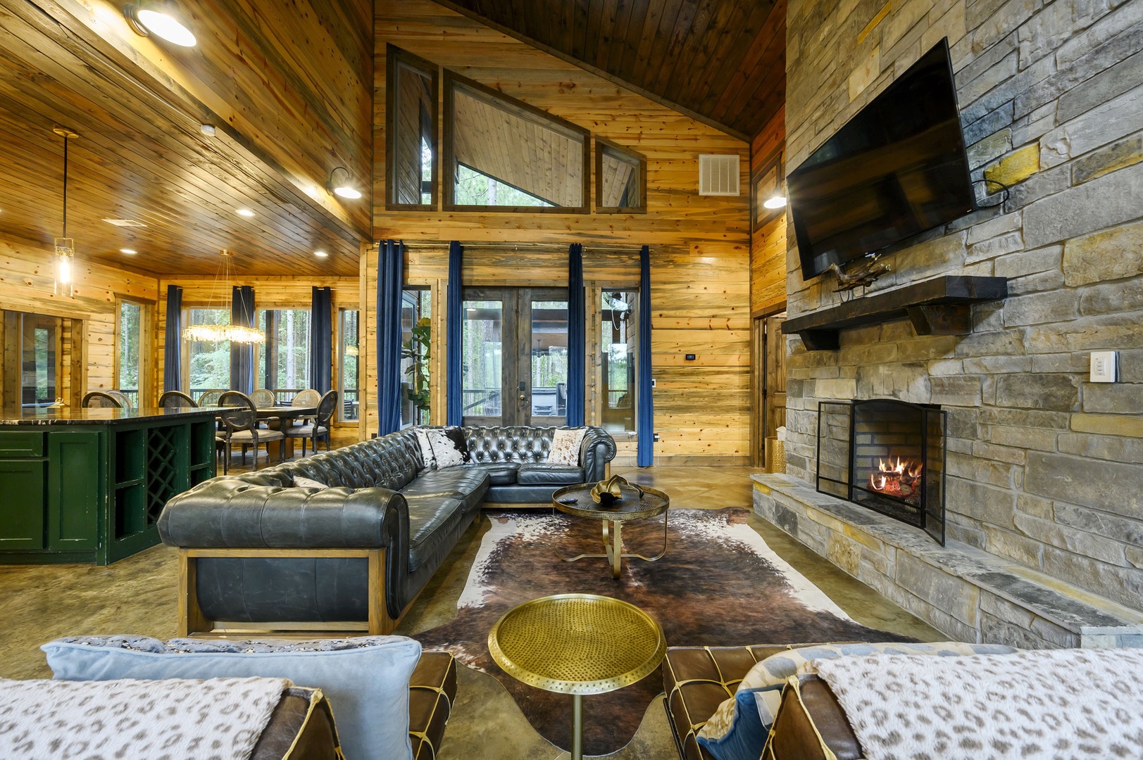 Unwind in this open, soaring living space with vaulted pine ceilings, plush tufted seating, and a striking stone fireplace that invites you to relax in style and comfort.