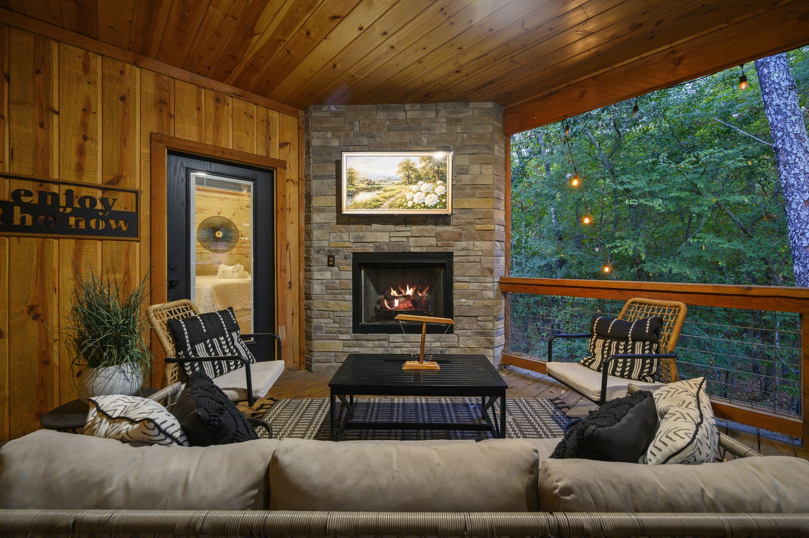 Sink into plush seating on your private covered deck, where a gas fireplace and string lights create the perfect evening retreat. Watch the forest come alive around you while staying cozy under the vaulted wood ceiling.