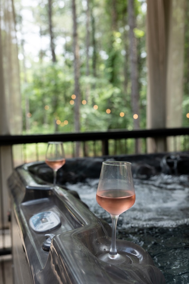 Soak in your private hot tub surrounded by towering pines, with soft lighting and a cozy cabin deck creating the perfect woodland retreat for evening relaxation.