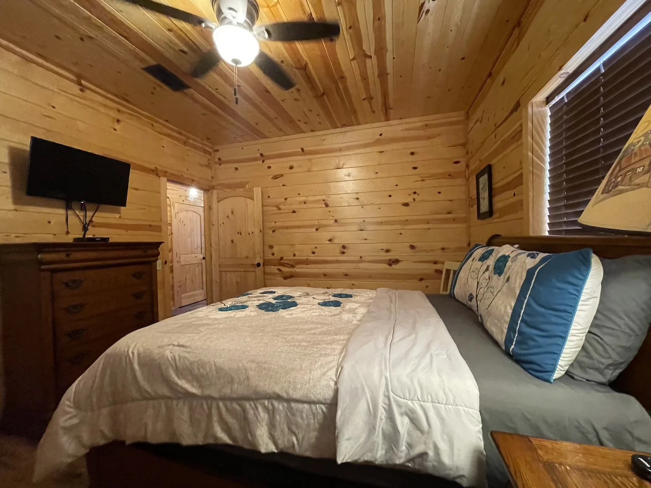 Sink into your plush bed surrounded by warm pine walls, where the ceiling fan keeps you cool and the rustic charm invites total relaxation.