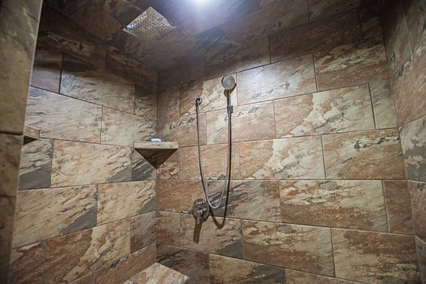 Step into your private spa-like shower with stunning natural stone walls and rainfall showerhead for a rejuvenating experience.