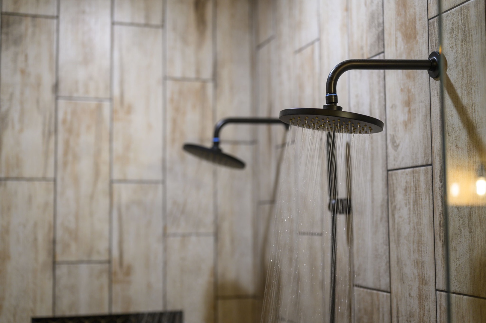 Dual rainfall showers with elegant bronze fixtures await your morning refresh, set against warm wood-look tile that brings a spa-like tranquility to your routine.