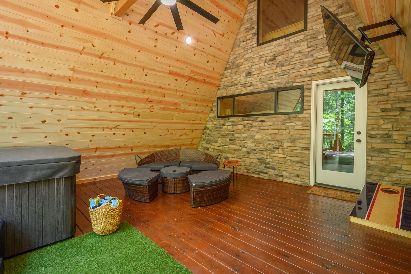 Unwind in your own private game room featuring a relaxing hot tub, cozy seating, and classic cornhole—perfect for fun-filled evenings after a day of adventure.