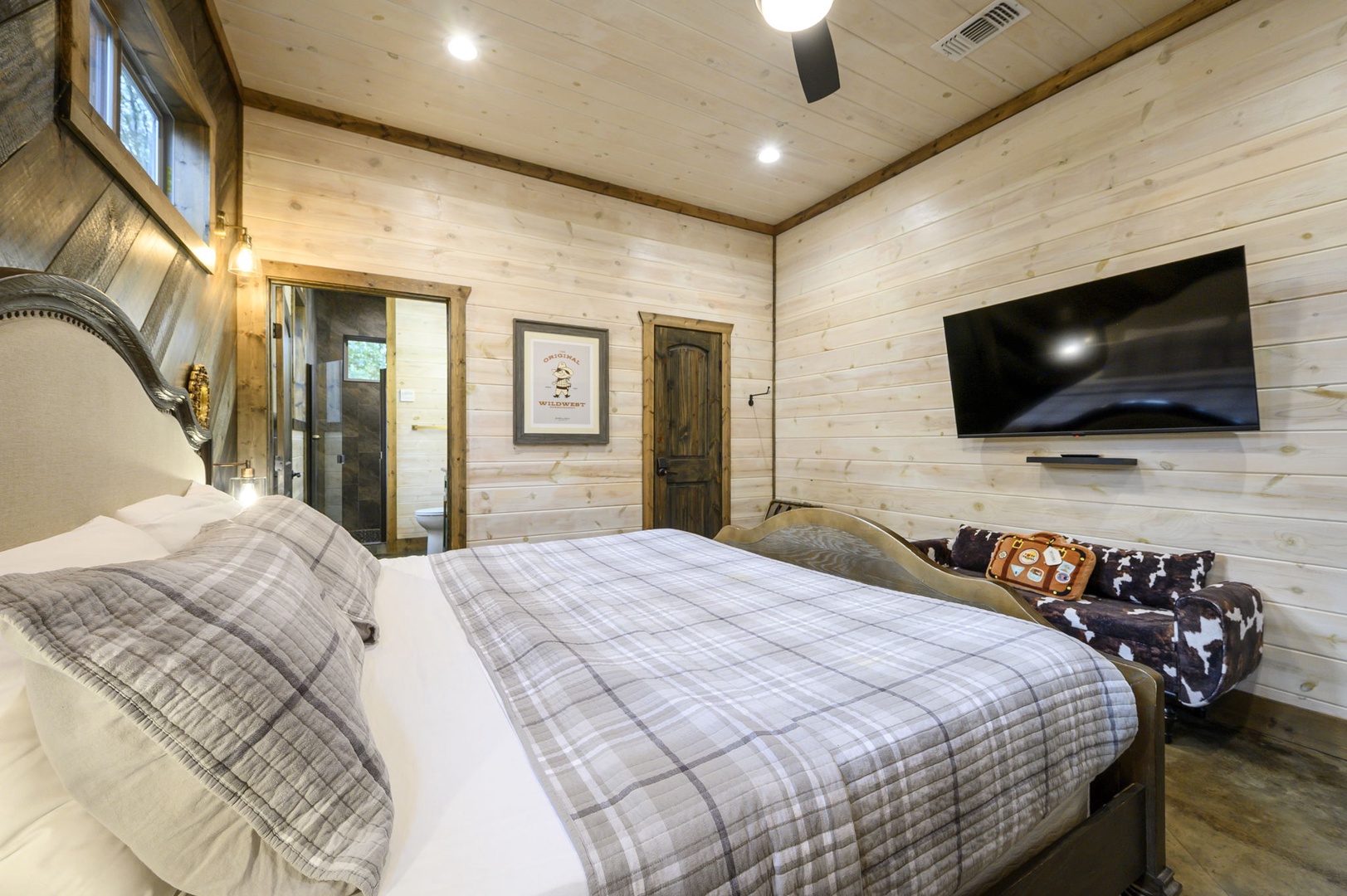 Sink into your cozy bed surrounded by warm wood-paneled walls that give this room a rustic, cabin-like charm. The soft plaid bedding and inviting bench at the foot create a peaceful retreat after your day's adventures.