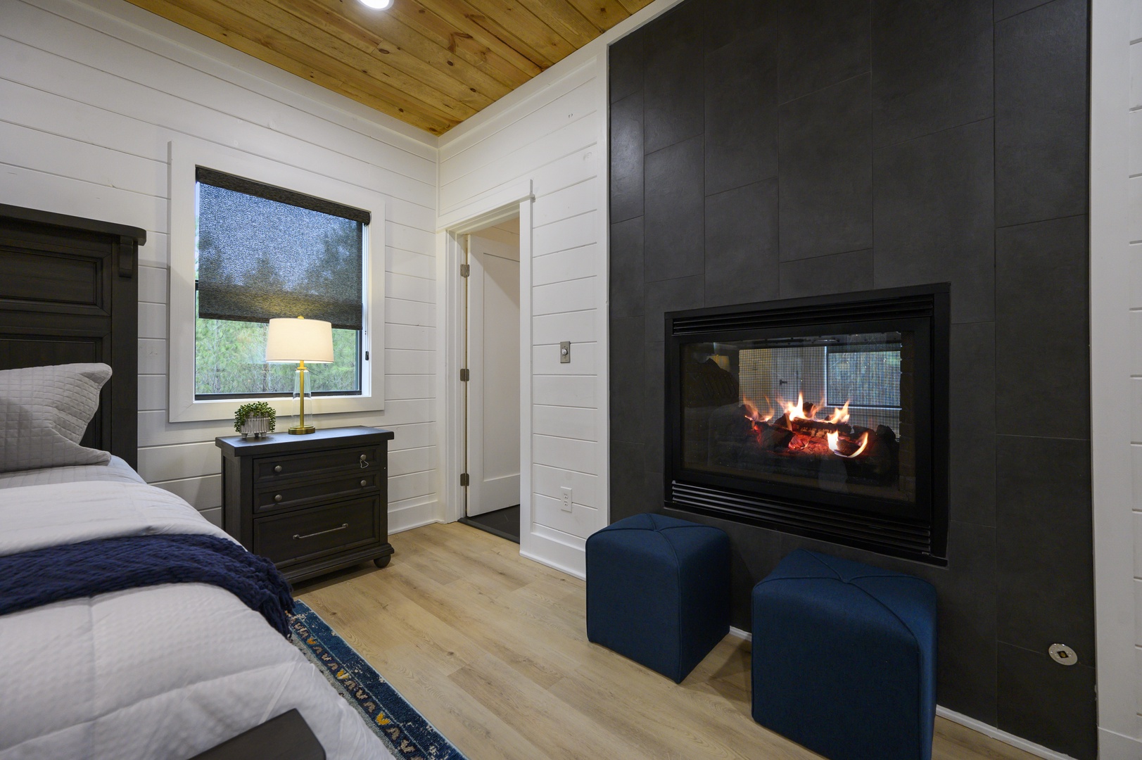 Drift off to sleep beside your own crackling fireplace in this cozy bedroom with rustic wood ceiling and charming details.