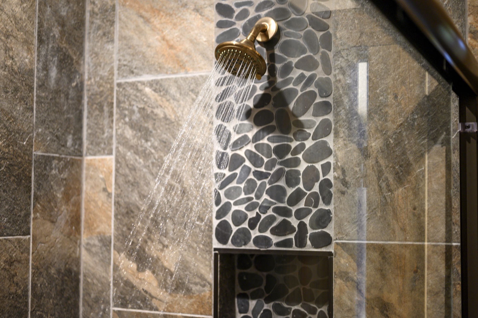 A spa-inspired shower awaits, featuring natural stone tile and a bronze rainfall showerhead that invites you to unwind after exploring the area.
