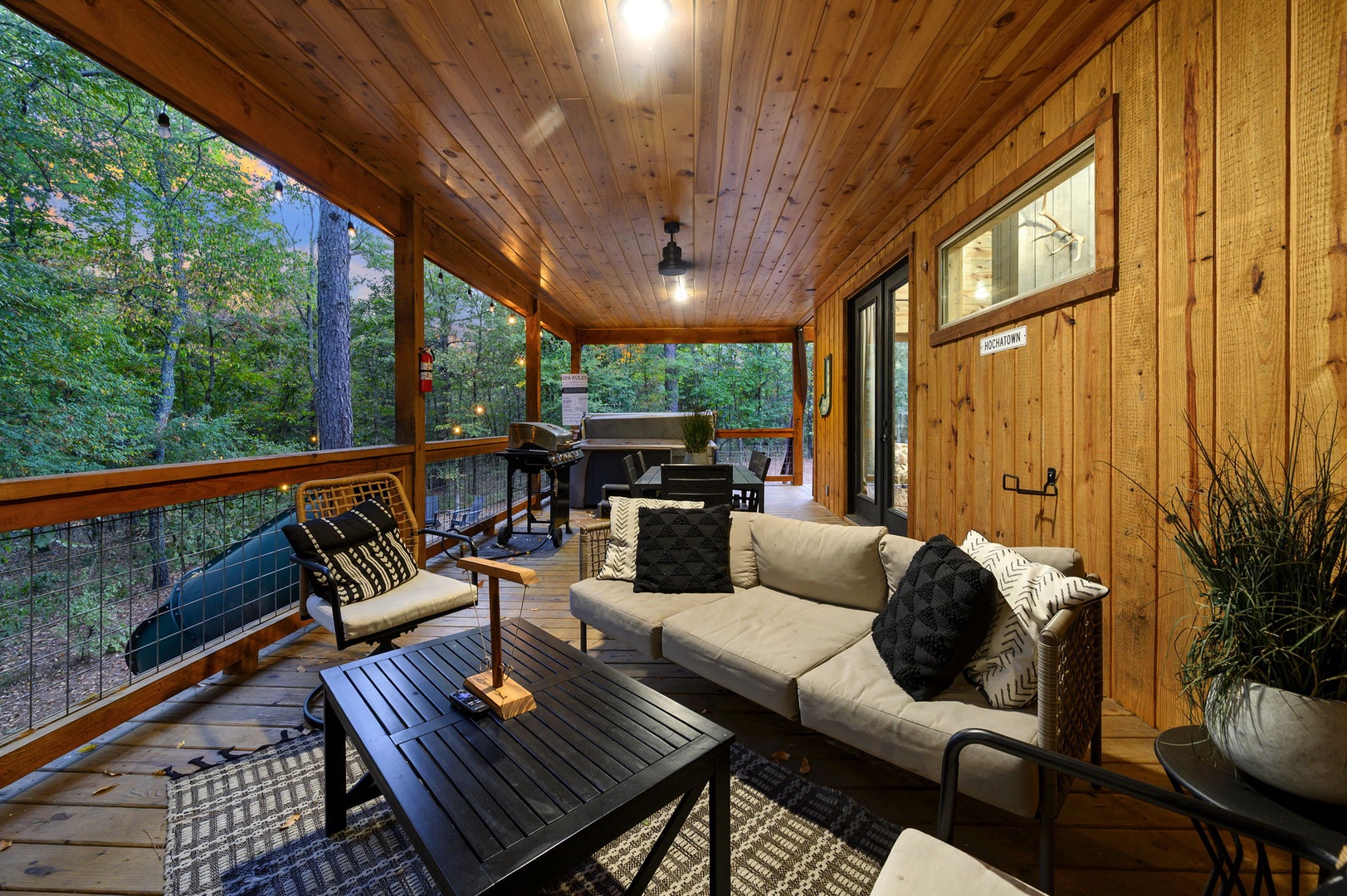 Settle into your private screened porch, surrounded by warm wood and forest views, where you can unwind on cozy seating or fire up the grill for an evening under the trees.