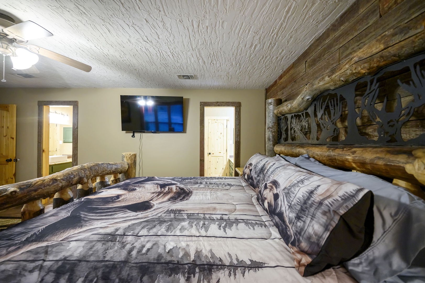 Rest easy in your rustic log bed with handcrafted wildlife headboard, enjoying modern comforts and textured ceiling details.
