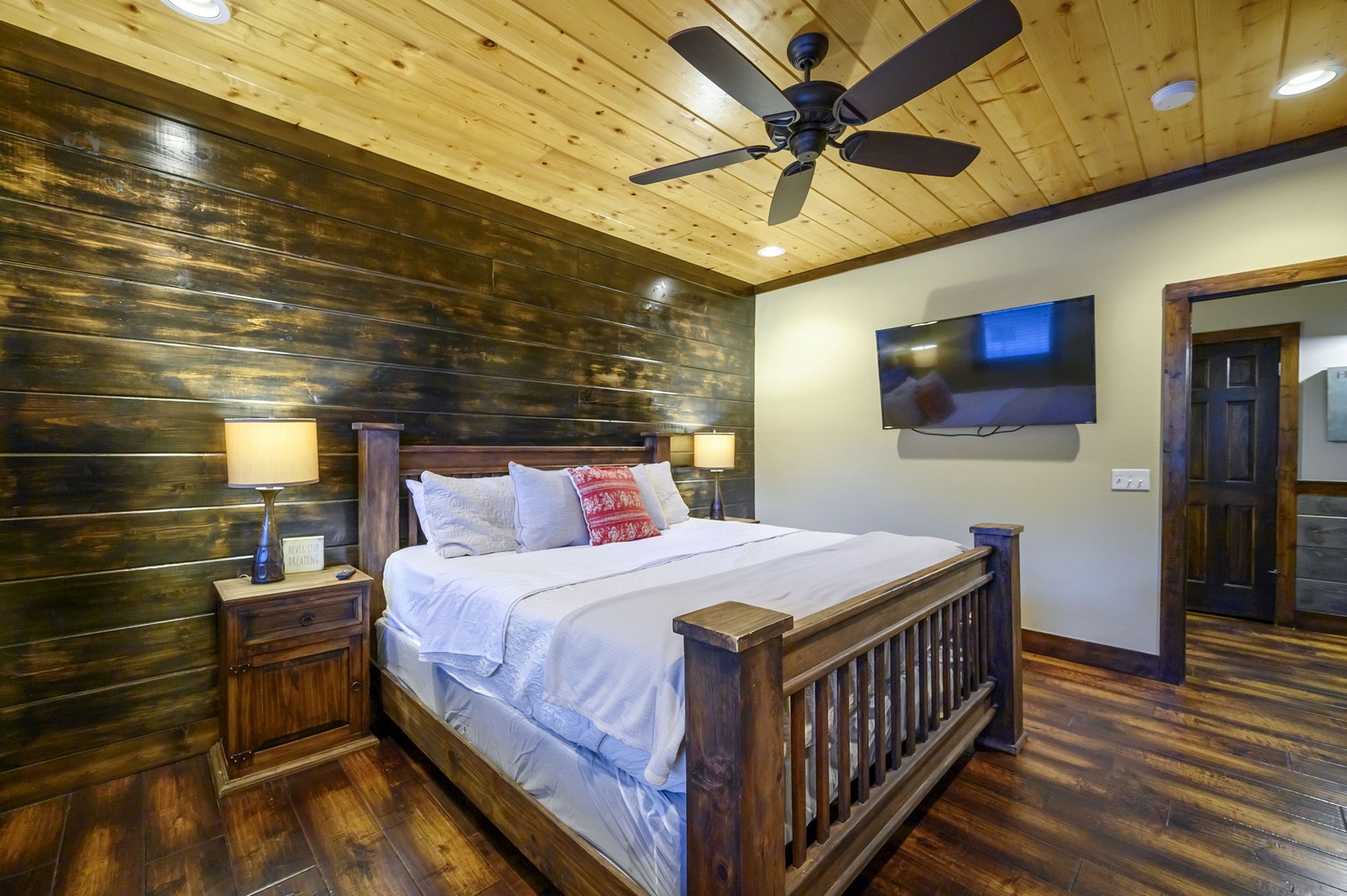 Unwind in your cozy bedroom featuring rustic wood walls, plush bedding, and a warm cabin atmosphere that invites restful sleep.