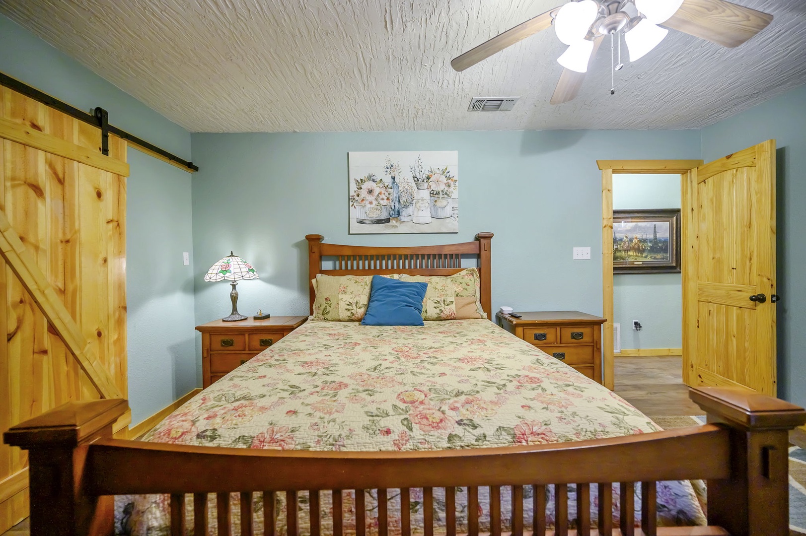 Relax in your cozy bedroom featuring warm wood furnishings, a rustic barn door, and charming cottage-style decor that creates the perfect peaceful retreat.