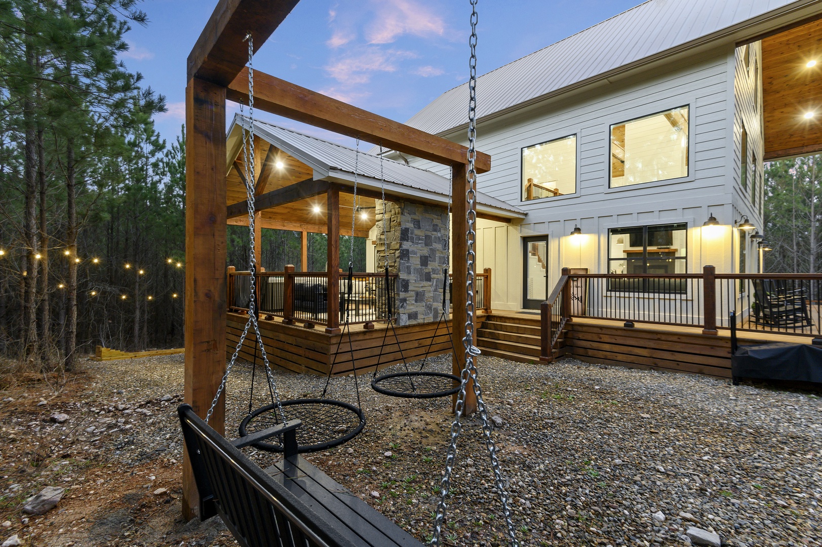 Modern mountain retreat with a playful swing set in your private backyard, surrounded by tall pines and outdoor lighting for magical evenings.