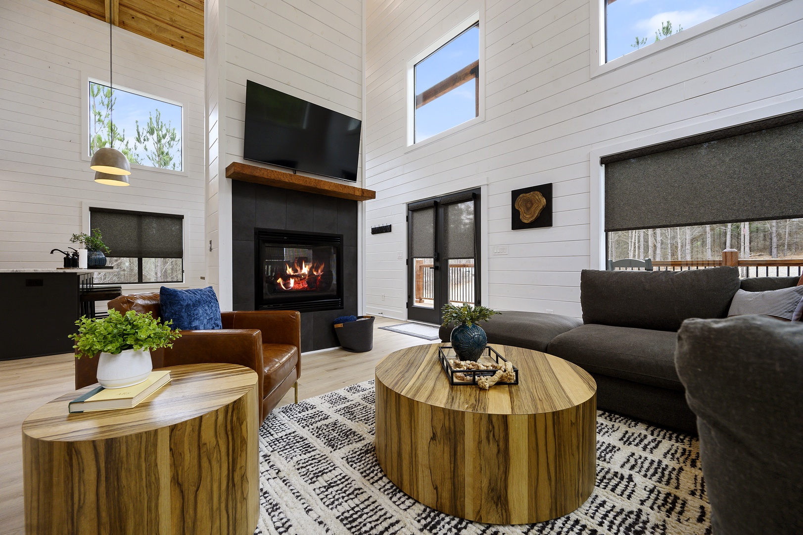 Unwind in your stylish living room with soaring ceilings, crackling fireplace, and cozy seating perfect for evening relaxation.