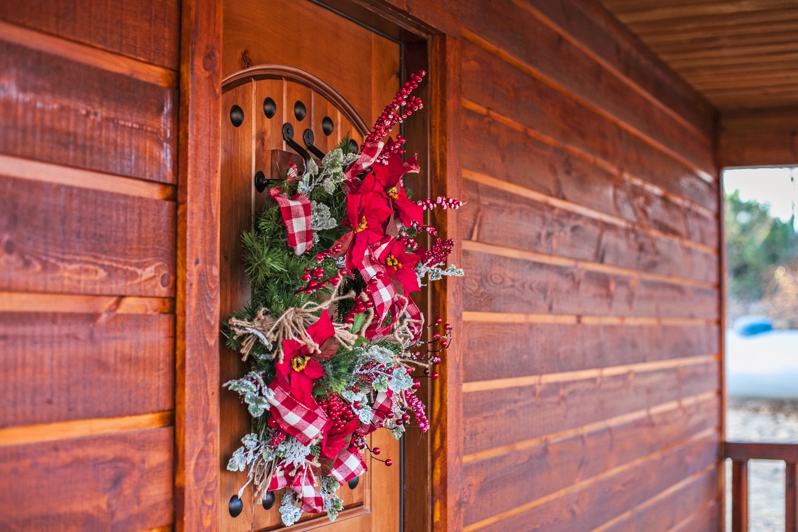 Step into the holiday spirit with this charming festive entrance, where rustic wood meets cheerful seasonal decorations for your perfect getaway.