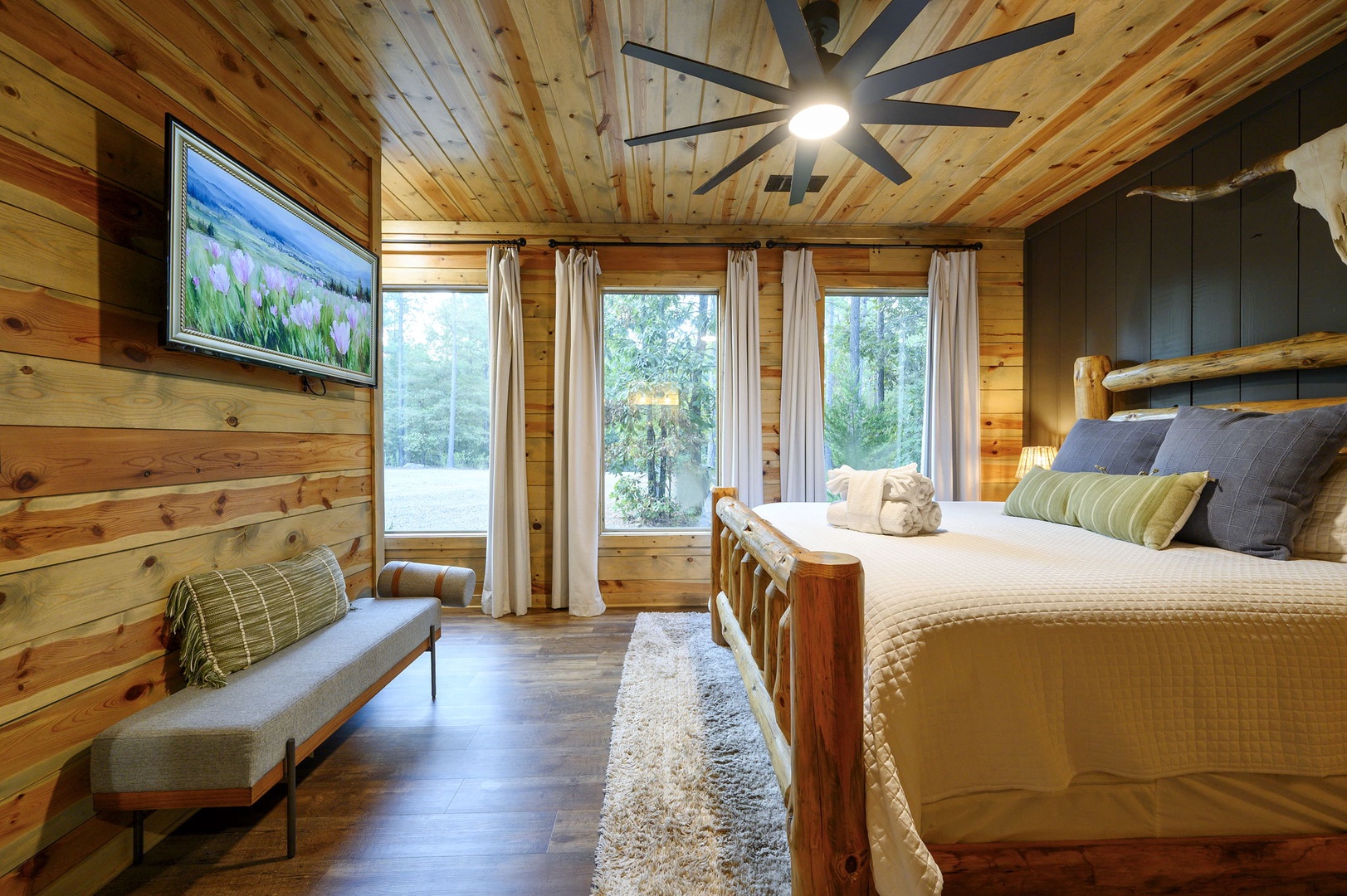 Sink into your plush bed beneath the warmth of timber beams and let natural light flood through large windows framing peaceful wooded surroundings.