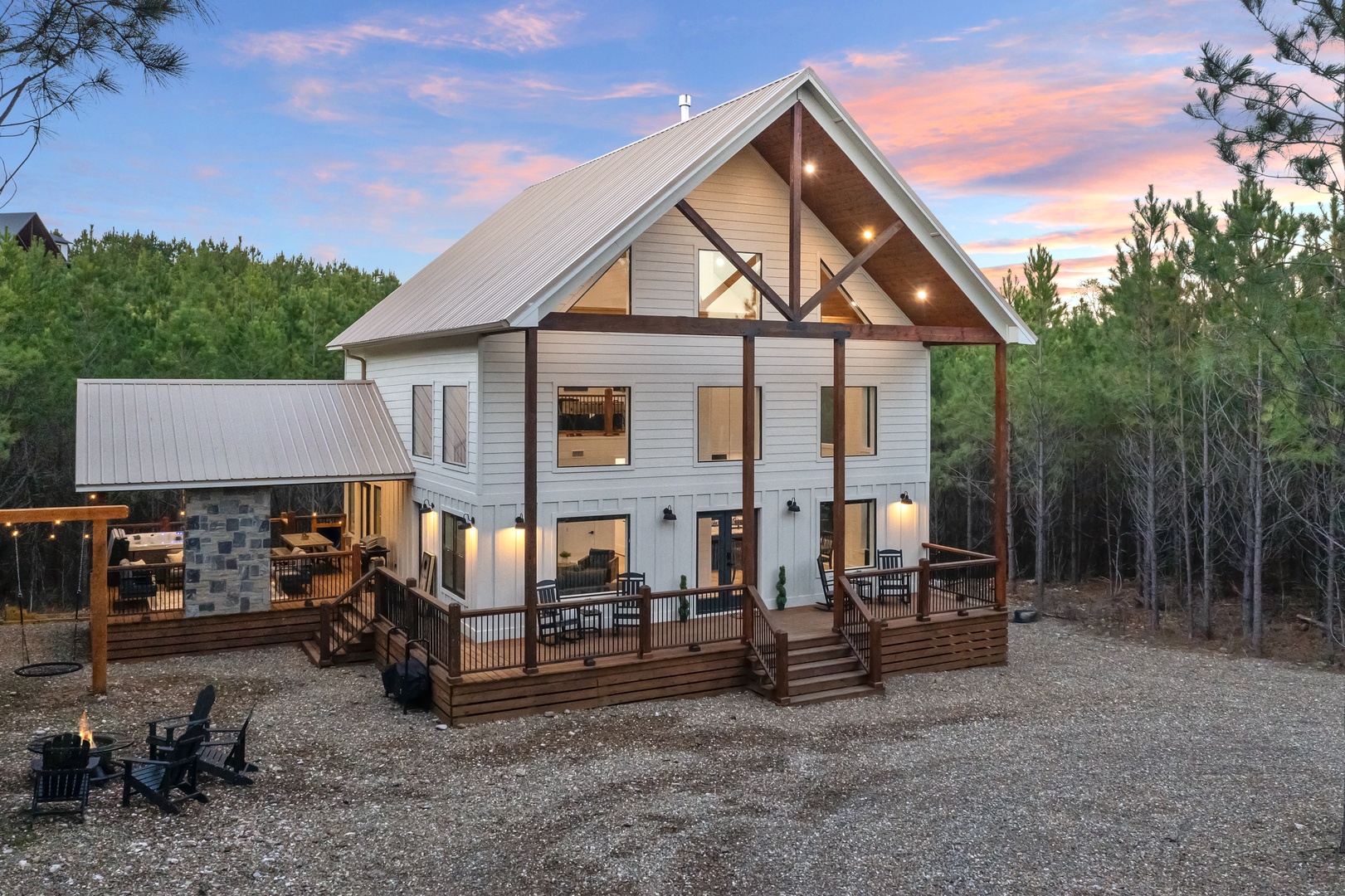 Modern cabin retreat featuring expansive covered porches, fire pit area, and forest surroundings for the perfect mountain getaway experience.
