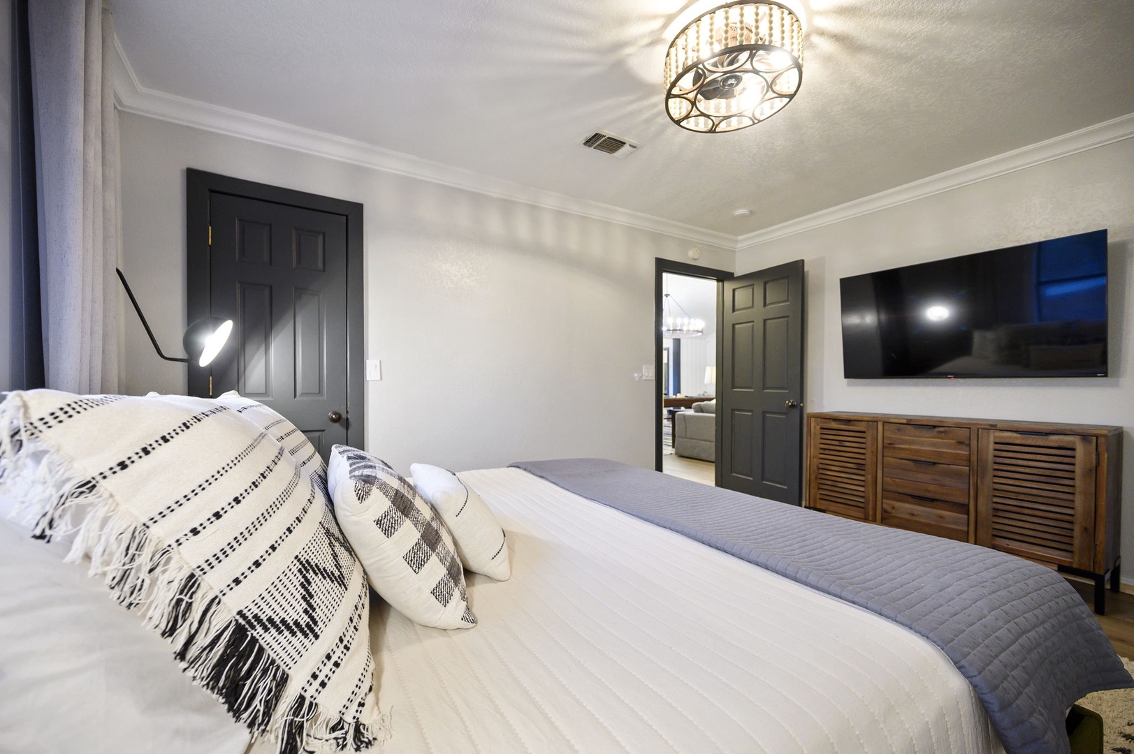 Drift into peaceful sleep in your elegantly appointed bedroom, where modern design meets cozy comfort beneath a stunning chandelier.