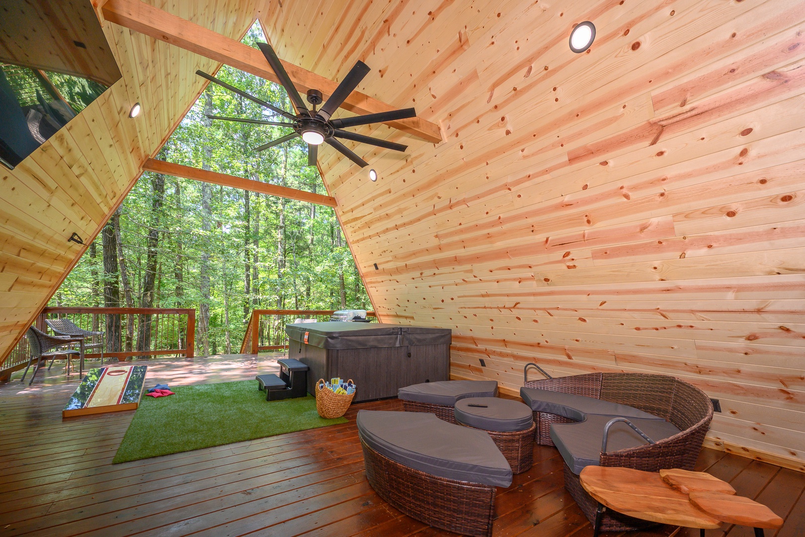 Your private forest retreat features a covered deck with hot tub and modern lounge seating, surrounded by towering trees that bring nature right to your doorstep.