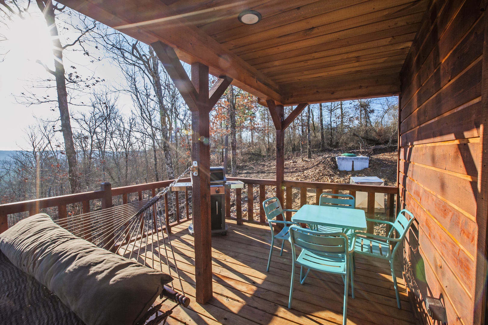 Relax on your private covered deck with mountain views, outdoor dining, and cozy seating under rustic wooden beams.