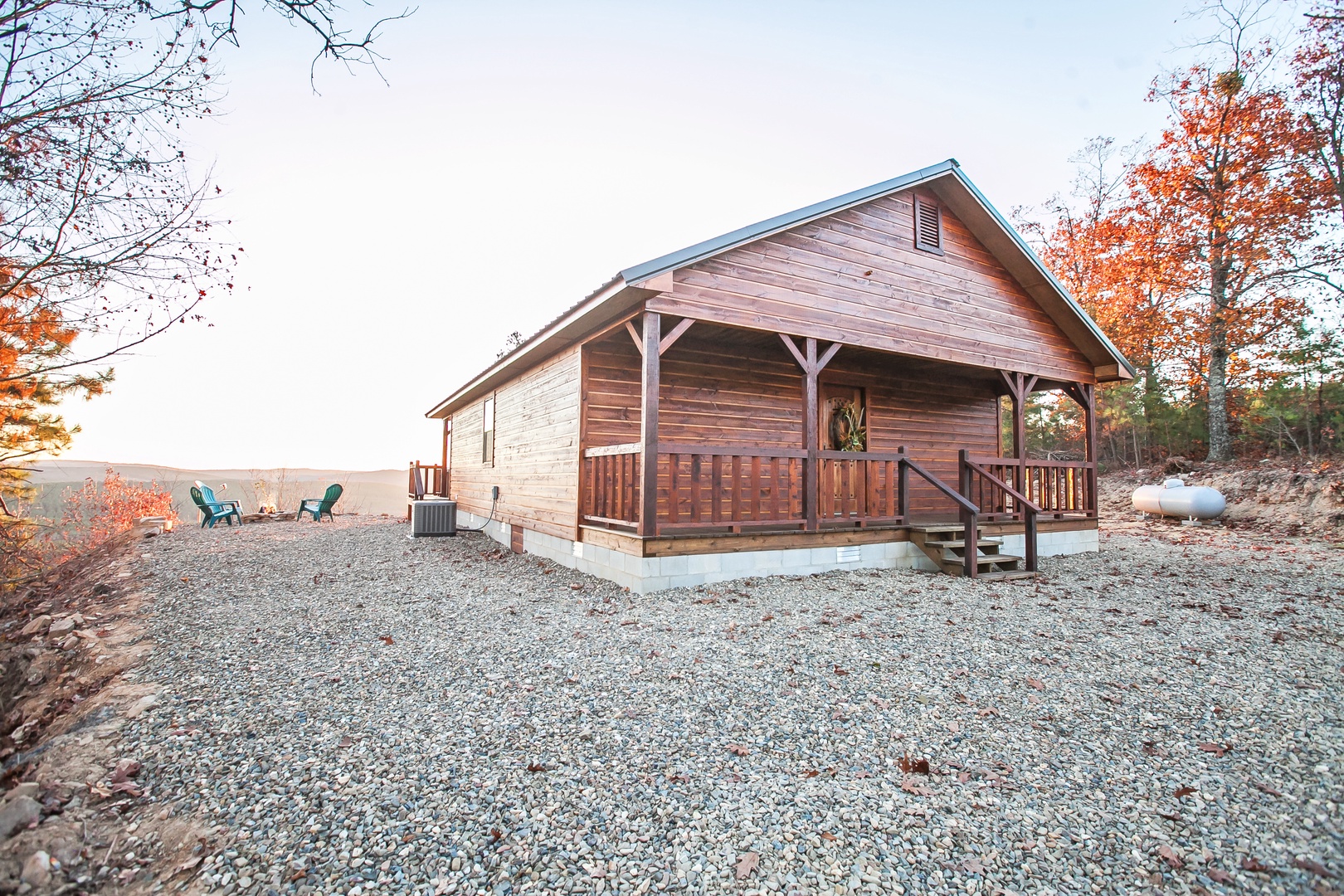 Charming log cabin nestled among vibrant autumn foliage with covered porch and mountain views in peaceful woodland setting.