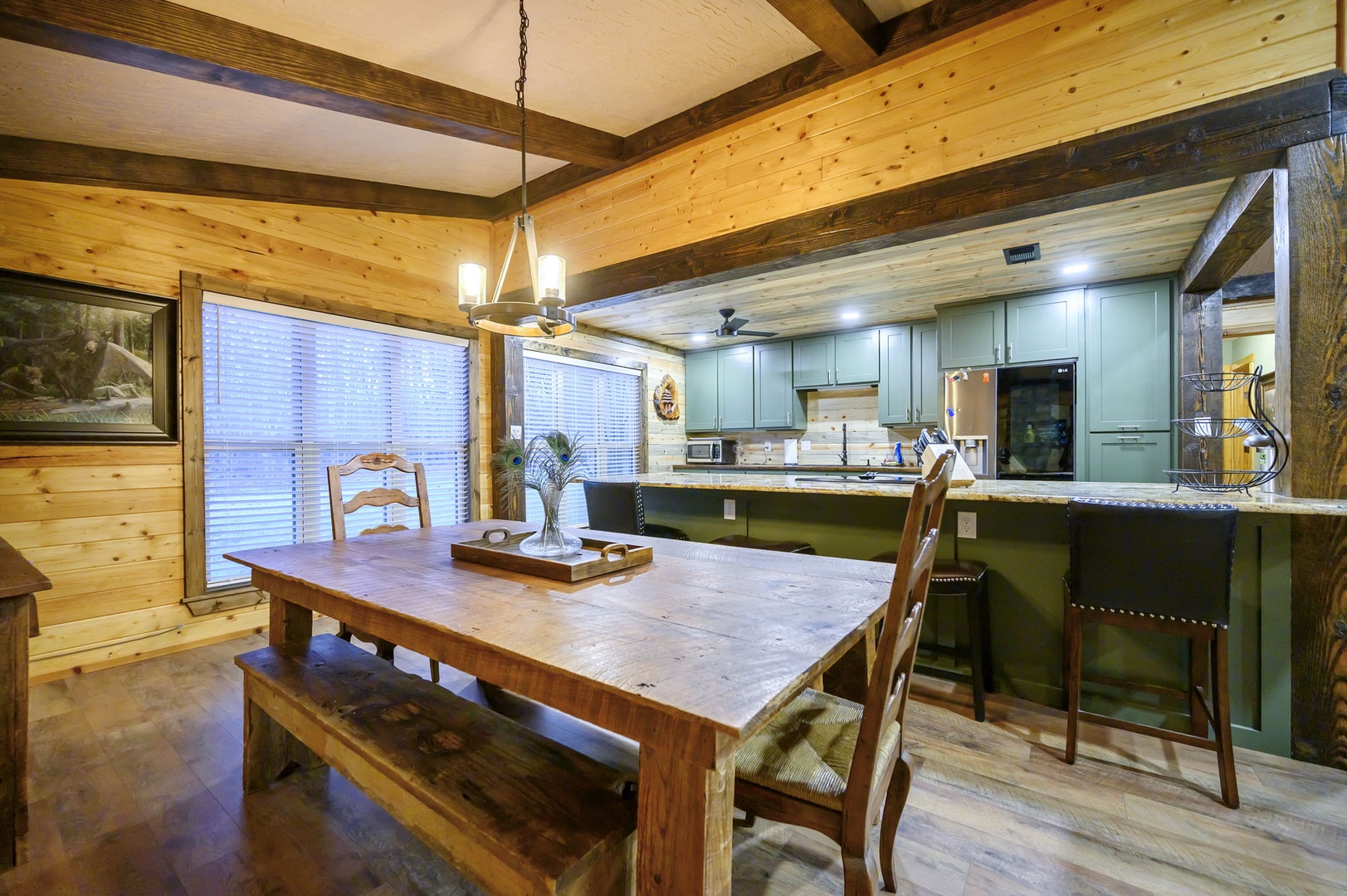 Gather around your spacious farmhouse table under warm pendant lighting, where rustic wood beams frame a fully equipped kitchen.